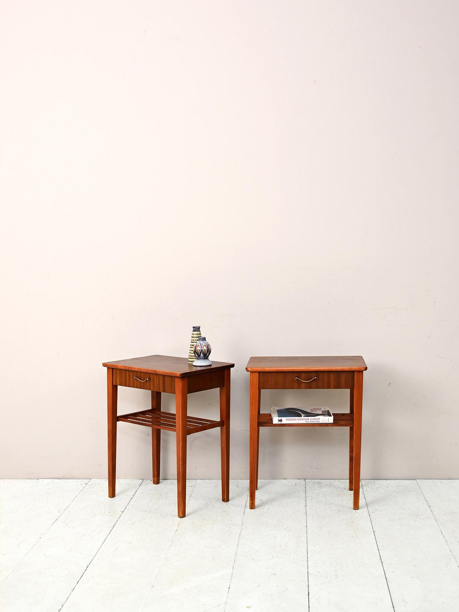 Pair of 1960s Scandinavian nightstands with drawer.

Characterized by classic lines and a retro look, they feature a magazine shelf and a drawer with a gold metal handle.
The long legs and clean lines lend modernity and elegance to the entire