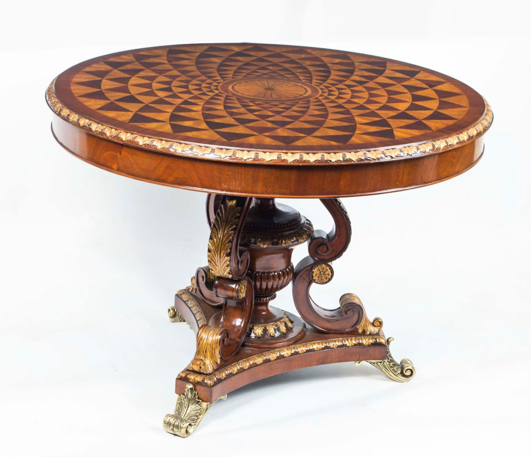 This is an  exquisite vintage mahogany Regency Revival  parquetry 'trompe l'oeil' centre table,  dating from the second half of the 20th Century.

The table is supported with a single central stem of hand carved mahogany with exquisite gilded