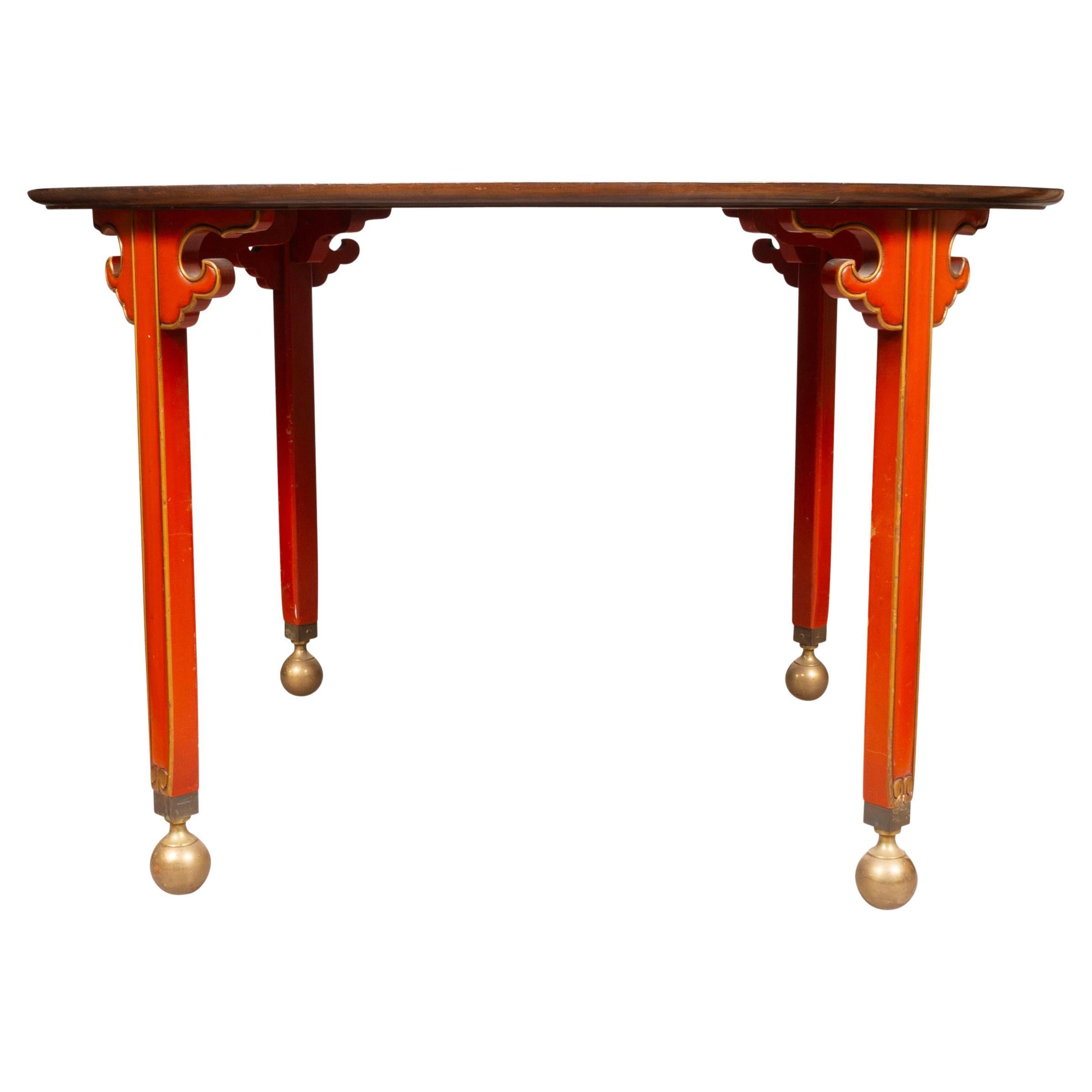 Circular mahogany top over a Chinese style red lacquer and gilt frieze. Square section legs and brass ball feet.