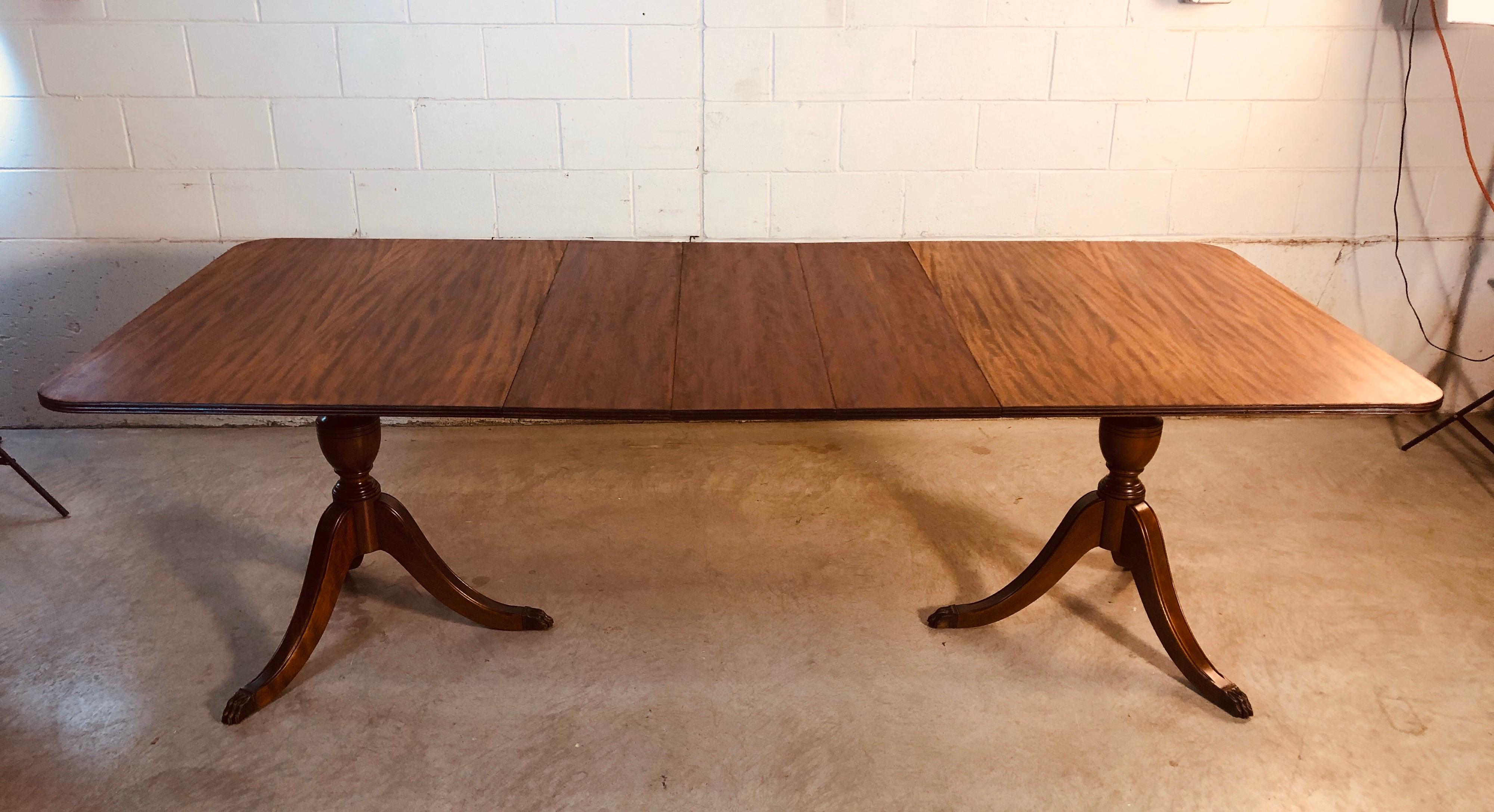 Vintage 1930s mahogany wood banquet style dining room table. The dining table is double pedestal and comes with three extra boards. The table is newly refinished and shows the mahogany grain. Table fully open, 95” L. Boards, 11” L each. Table