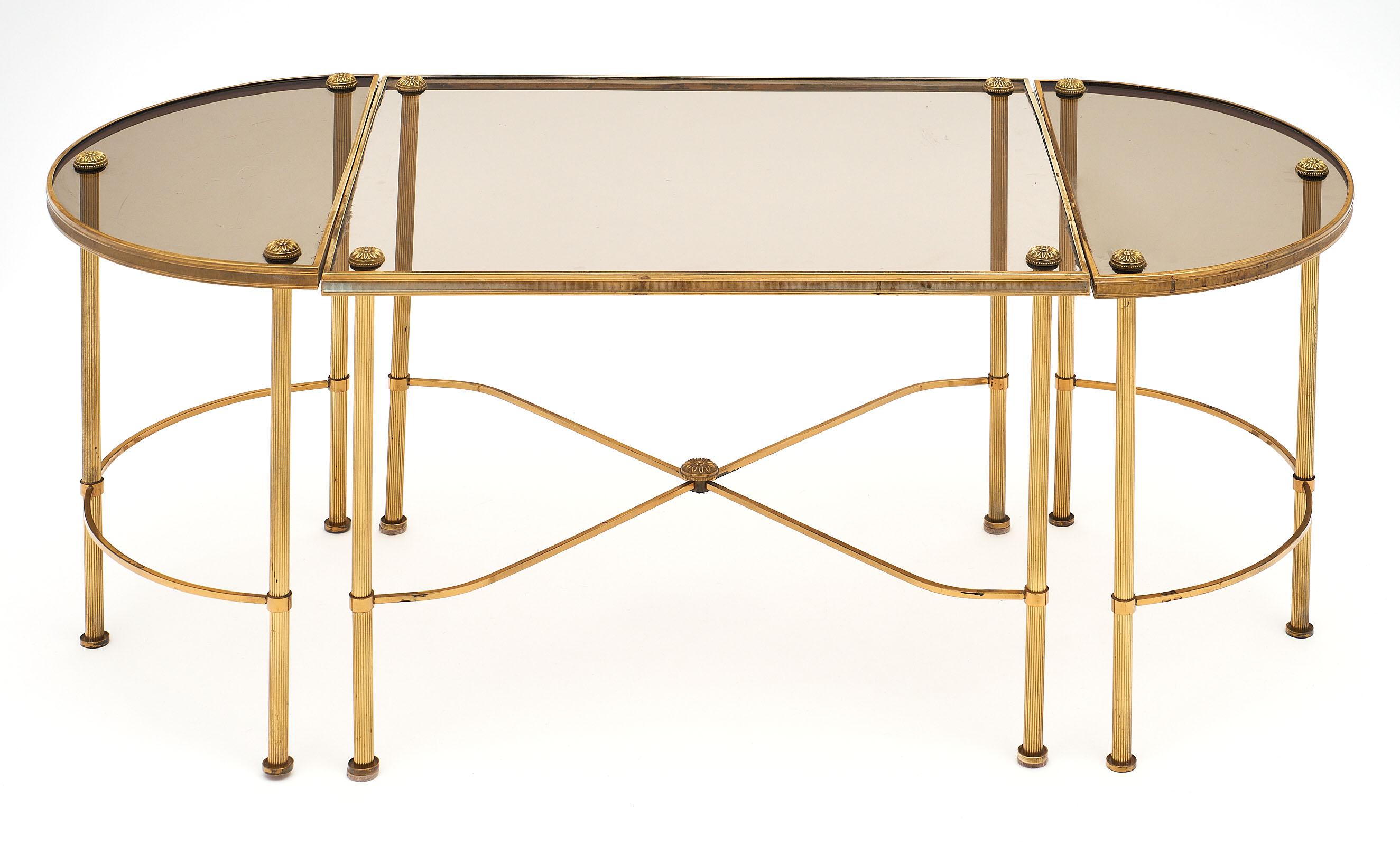 Maison Baguès style vintage coffee table from France. This Art Deco period piece has a brass structure and smoked glass, featuring a square table with two half moon side tables on each end. The curved stretchers, finely cast finials, and perfect