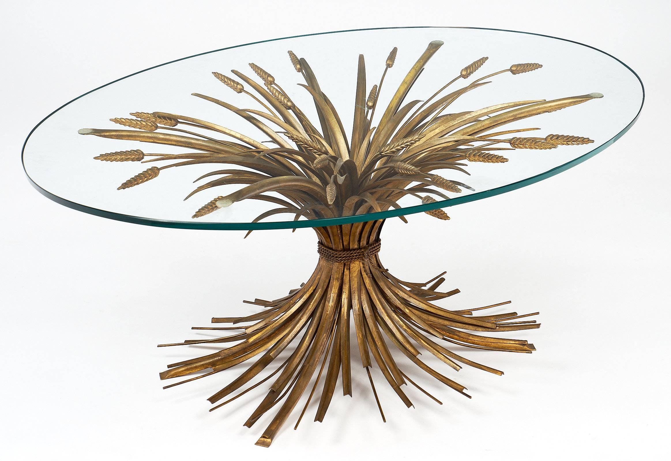 Vintage French Maison Baguès “sheaf of wheat” coffee table with a gold leafed brass base and an oval glass top. Historically, Salvador Dali gave Coco Chanel a similar table for her Paris apartment on Rue Cambon. The design is now a classic, highly