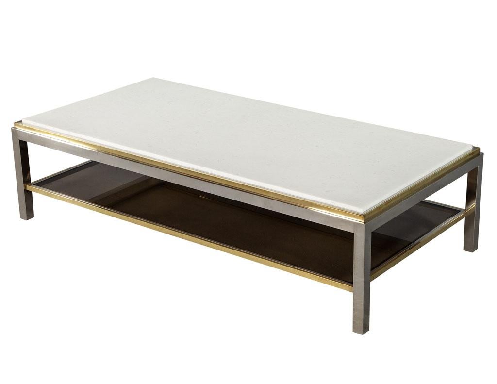 Vintage Maison Jansen cocktail coffee table. Featuring a new stunning white honed stone top. 2-tier design for storage underneath with sleek brass details on a stainless steel frame.