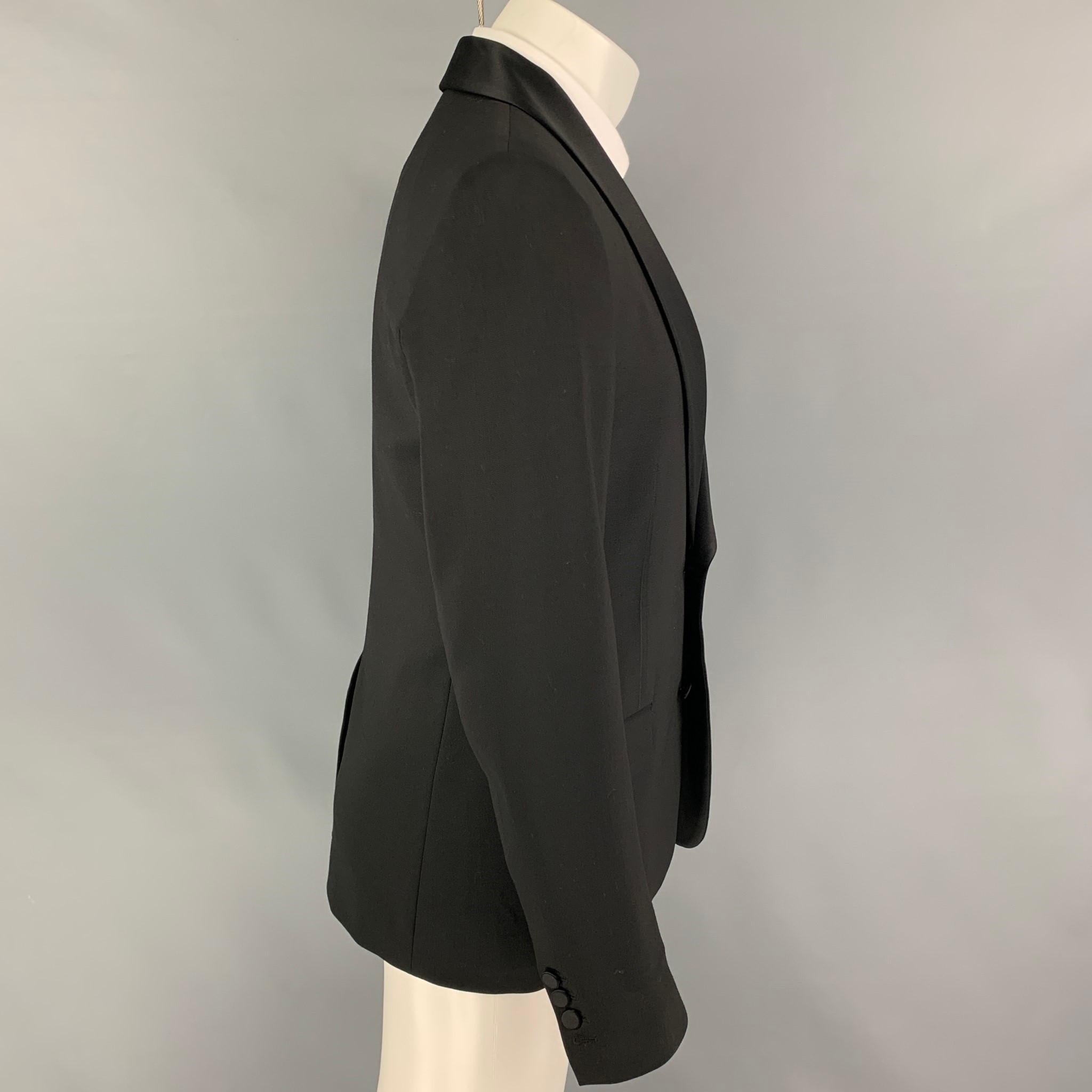 Vintage MAISON MARGIELA sport coat comes in a black polyester blend with a full liner featuring a shawl collar, flap pockets, single back vent, and a double button closure. Made in Italy.

Very Good Pre-Owned Condition.
Marked: