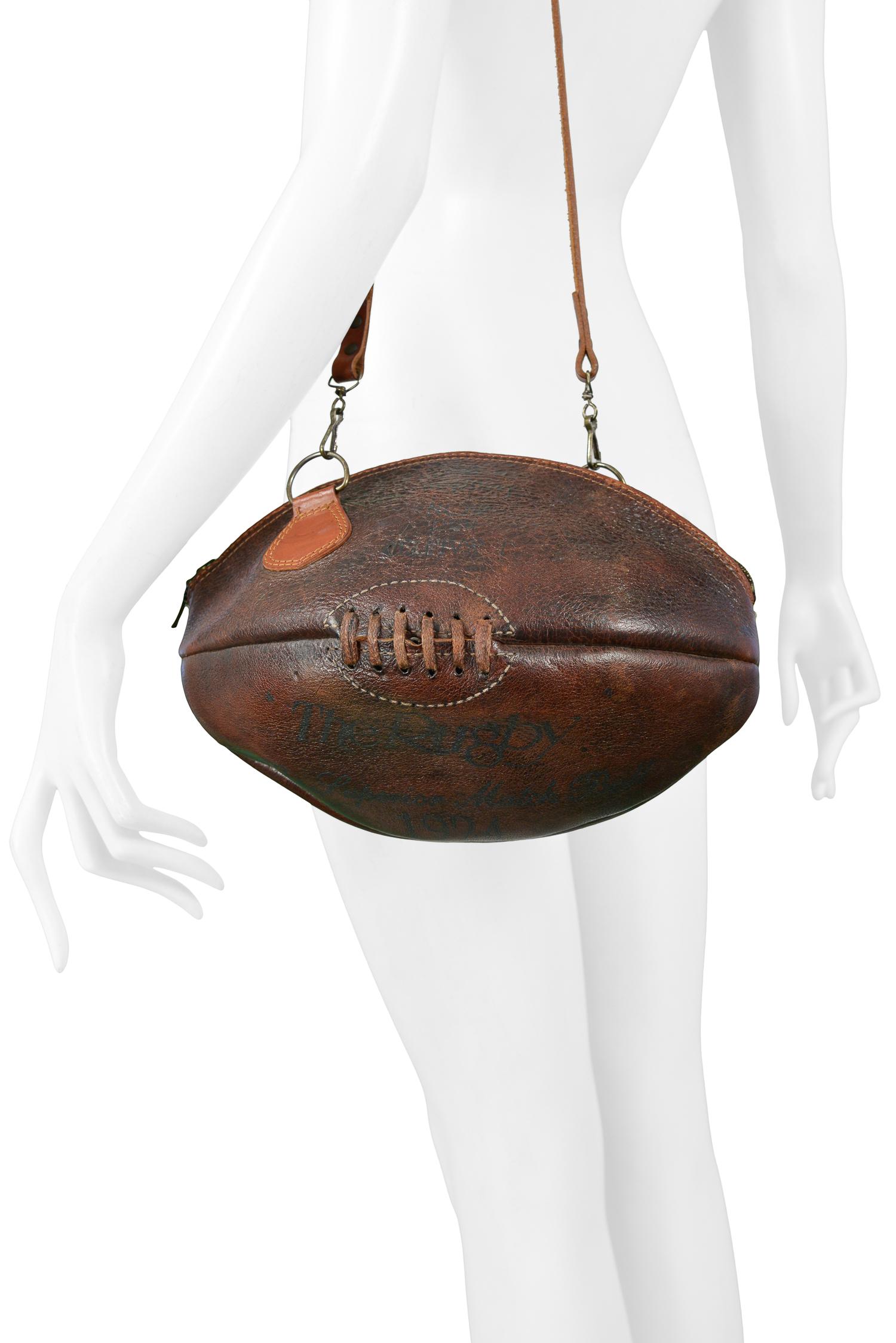 A rare and unusual vintage Maison Martin Margiela artisanal 0-collection rugby ball bag made from a vintage ball. The bag features a zipper closure, text graphic, and cross body strap. From the 2003 collection. 

Excellent Vintage Condition.