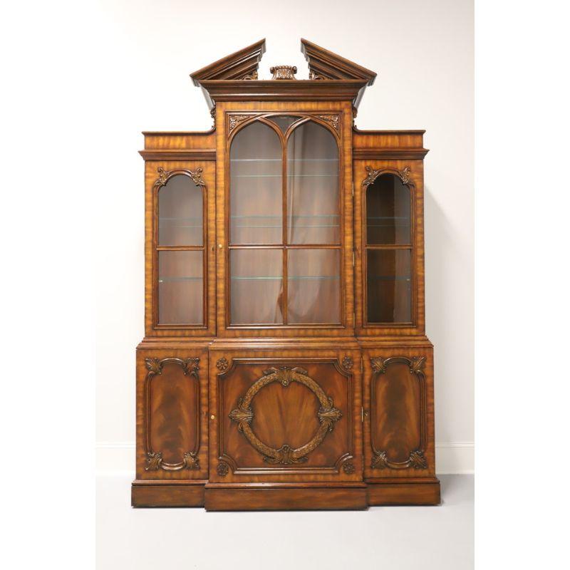 A Chippendale style china cabinet by Maitland Smith. Made in the Philippines in the late 20th Century. Aged mahogany and brass hardware. Upper cabinet capped with pediment, three glass pane doors, seven adjustable glass shelves (4 small, 3 large),