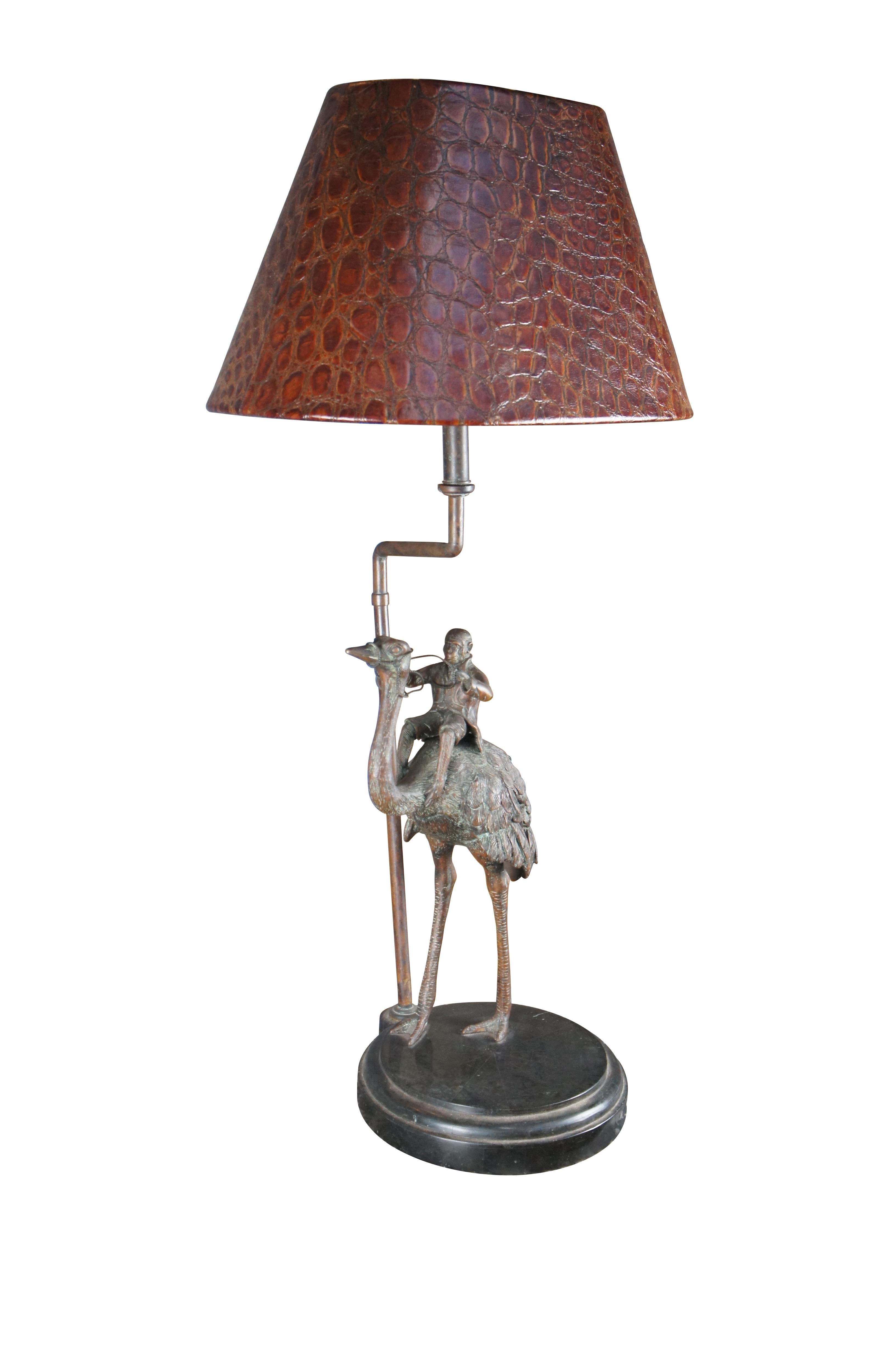 A charming late 20th century table lamp by Maitland Smith. Features a bronze Ostrich carrying a Monkey. The bronze is over a round tessellated marble base and includes a embossed ostrich pattern leather shade.

Dimensions:
39