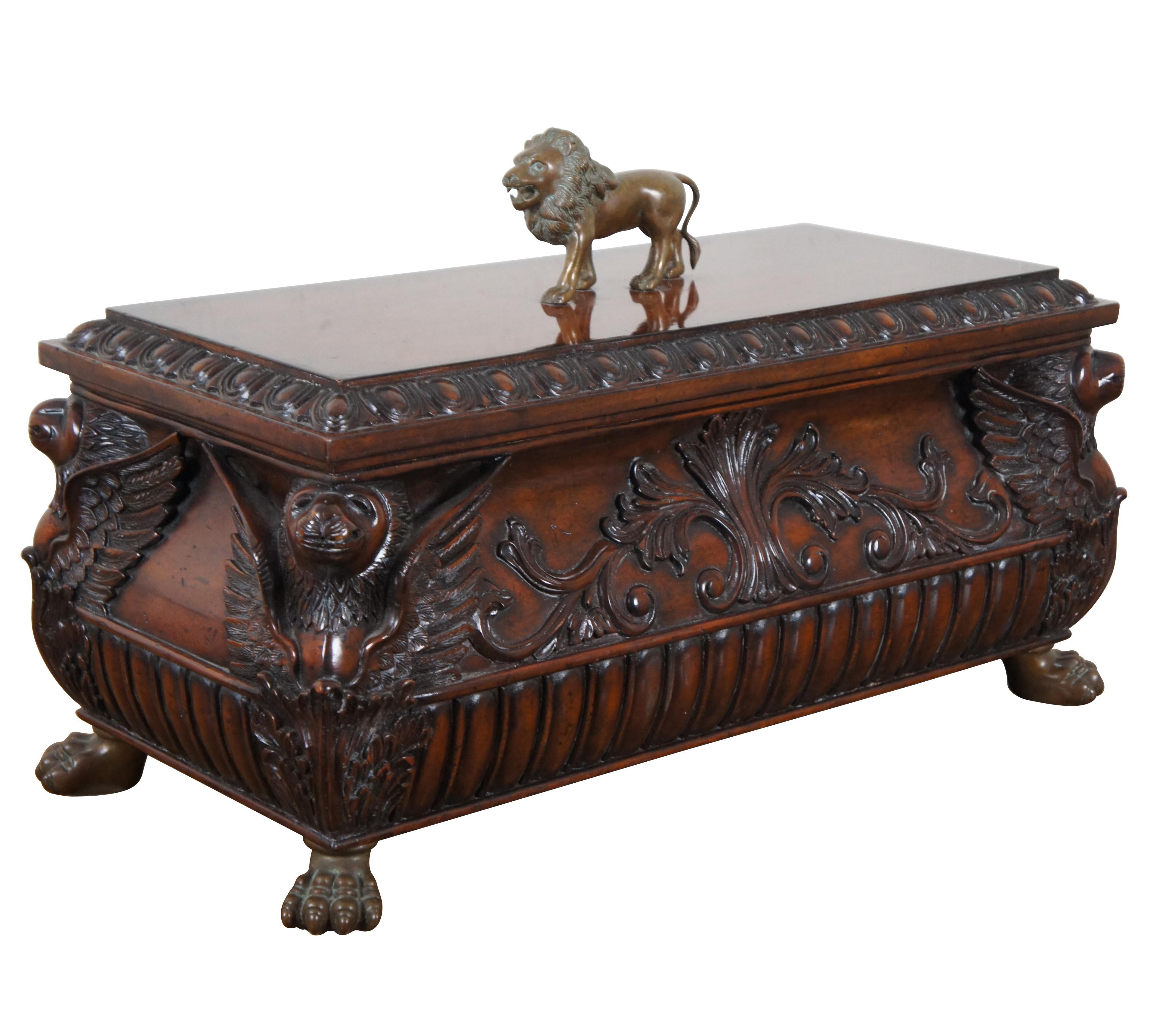 Vintage Maitland Smith mahogany box or chest carved with Neoclassical / Egyptian Revival foliate details and winged lion corners, supported on brass paw feet with a brass walking lion finial on the lid.