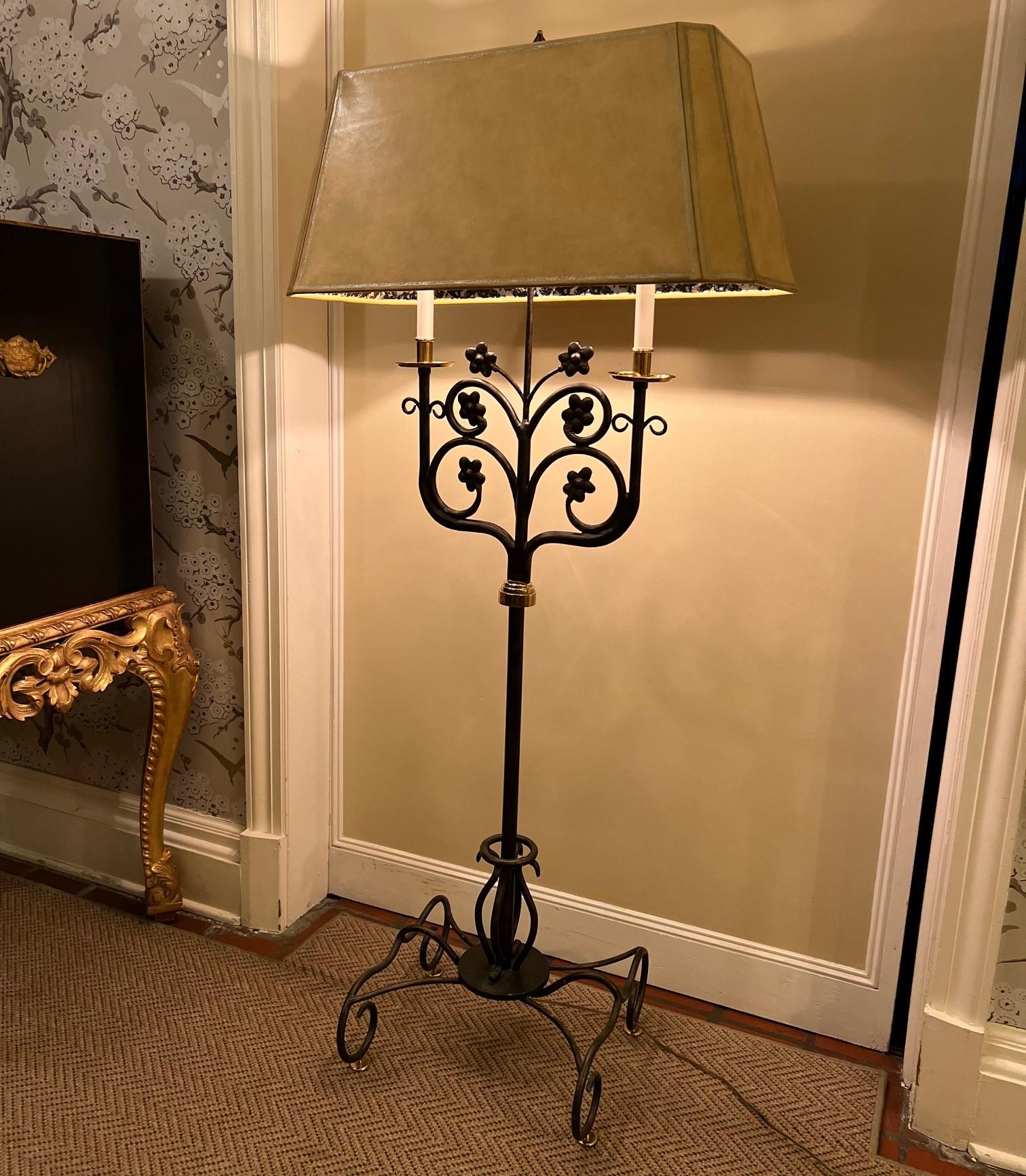 A vintage Maitland-Smith floor lamp made of brass and bronze with a leather shade. The base rises from brass disc feet leading to curling bronze elements then to a single bronze upright. The upright terminates with a brass detail issuing an