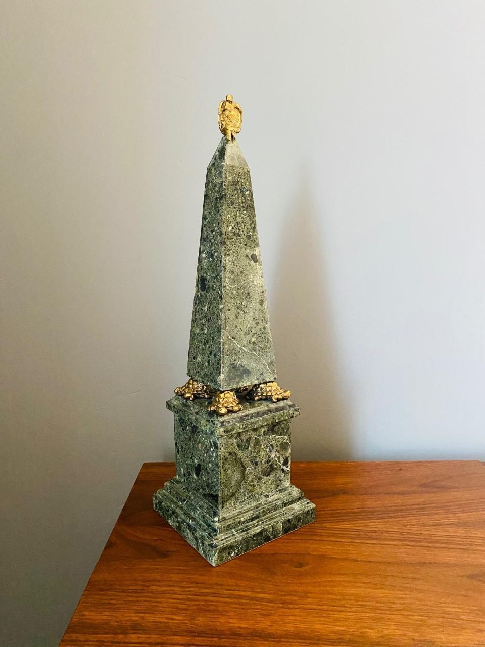 Beautiful green faux marble obelisk. The four-sided tapered obelisk has a turtle shaped brass tone metal finial and feet. It sits on a matching pedestal that is lined to the underside with felt. The piece is signed and numbered. This sculptural