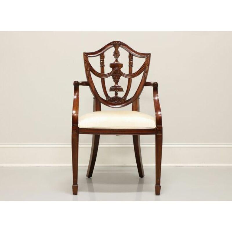 A Hepplewhite style armchair by Maitland Smith. Mahogany with decoratively carved back, curved arms, cream color fabric upholstered seat, straight legs and spade feet. Made in Indonesia, in the late 20th century.

Measures: Overall: 22 W 19 D 39