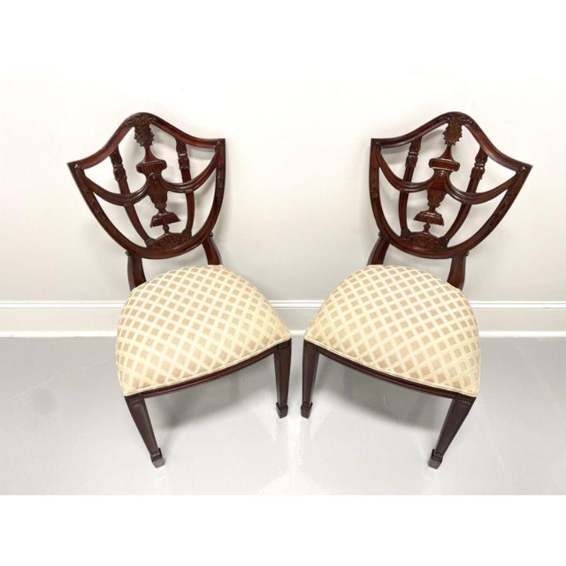 A pair of Hepplewhite style dining side chairs by Maitland Smith. Mahogany with decoratively carved back, cream & gold color patterned fabric upholstered seat, straight legs and spade feet. Made in Indonesia, in the late 20th Century.

Measures: