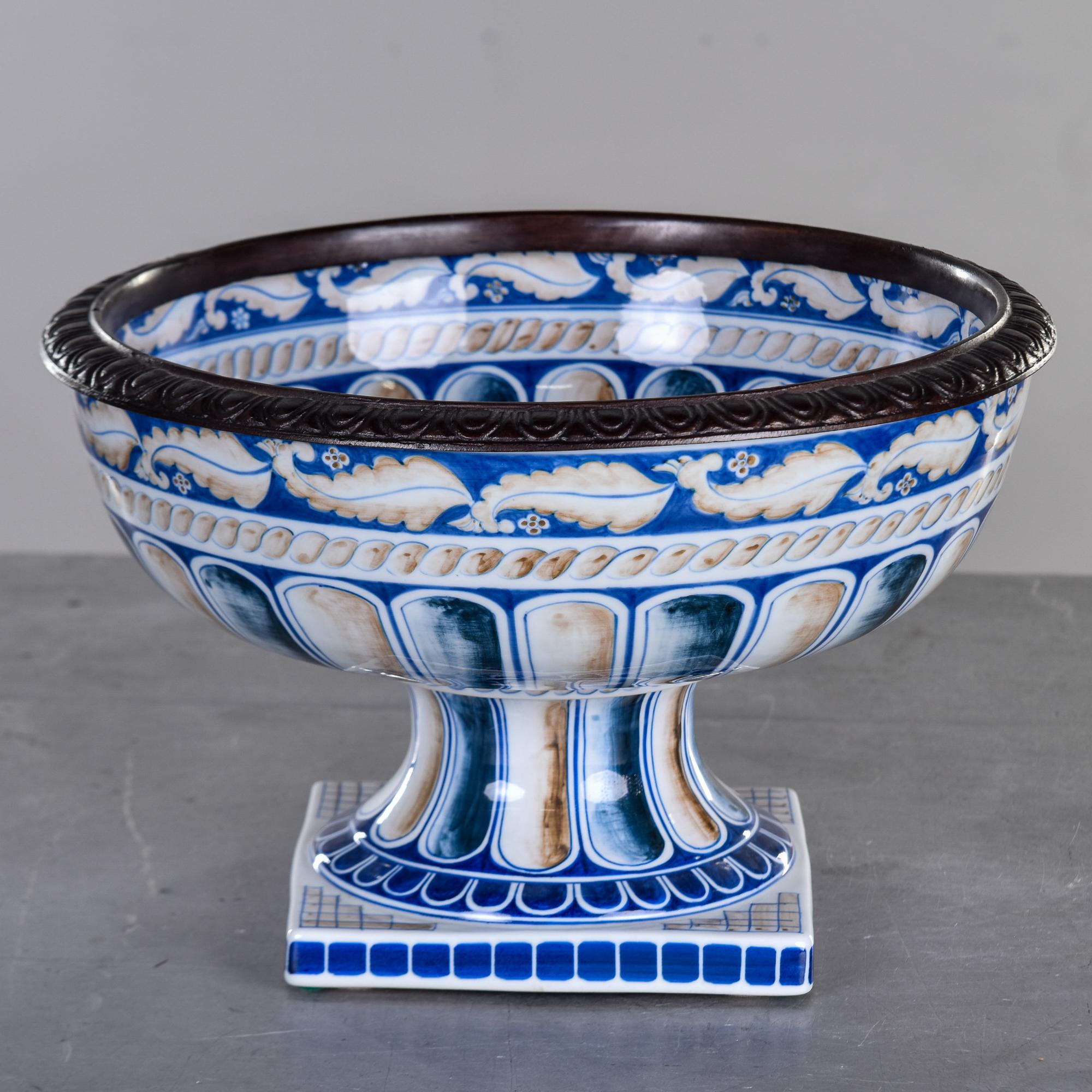 Large circa 1980s pedestal bowl in blue, white and pale brown glaze with leaf and rope braid motif by Maitland Smith. Square pedestal base supports a bowl just under 15” diameter with a decorative bronze rim. No flaws found. Maker’s mark on