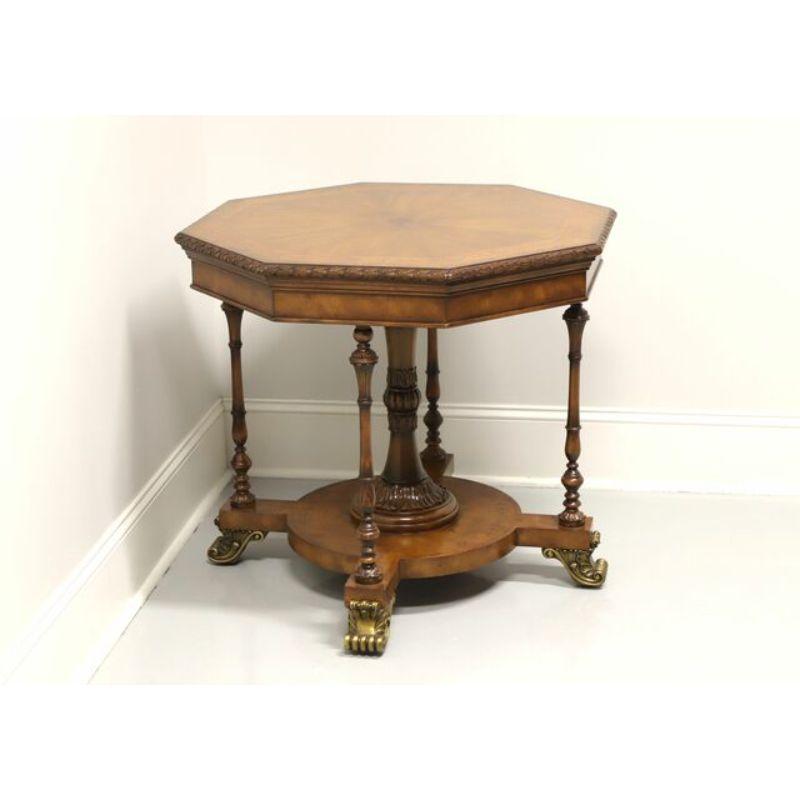 An octagonal accent table in the Regency style by Maitland Smith. Mahogany with banded and inlaid top, a carved edge, intricately carved pedestal, decorative turned support legs and brass scroll feet. Hand made in the Philippines, in the late 20th