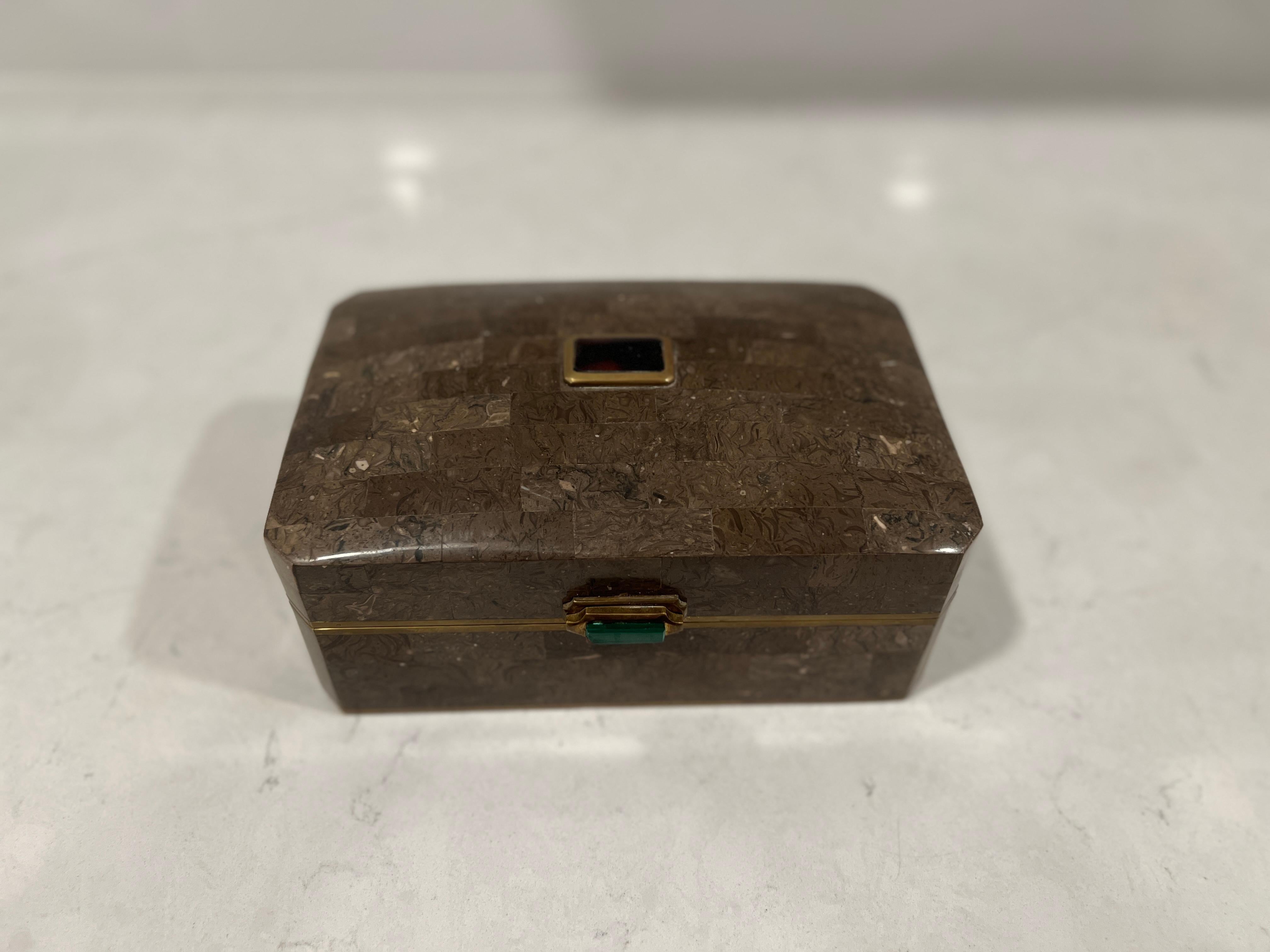 A vintage light brown tessellated stone box mounted with brass banding. The front hinge is adorned by a rectangular piece of carved malachite, and a finial with a deep amethyst colored stone. Original label affixed to underside. 

