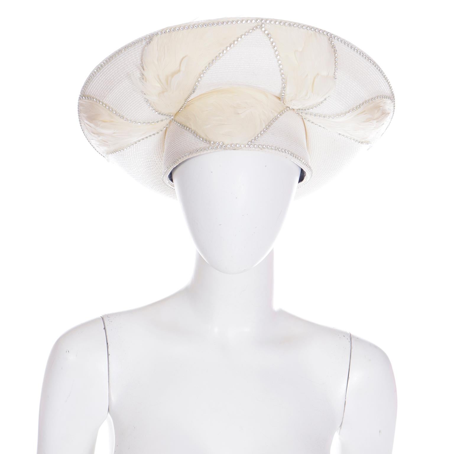 This lovely unique, dramatic vintage hat is from Makins New York. The hat is made of coated white straw, cream feathers and rhinestones. This wide brim, high angled hat has beautiful rhinestones outlining the brim, headband and feathers.
We acquired