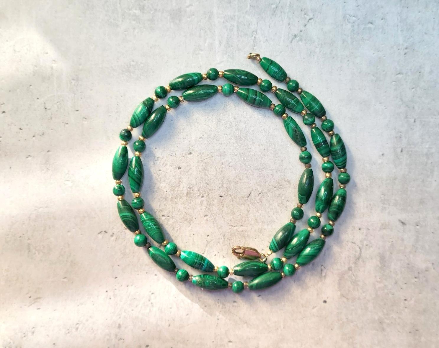 This necklace has a length of 20.5 inches (52 cm) and features smooth barrel beads measuring 12mm x 5mm and small round beads measuring 4mm. The color of the beads ranges from deep dark green to light green shades, and within the same stone, there