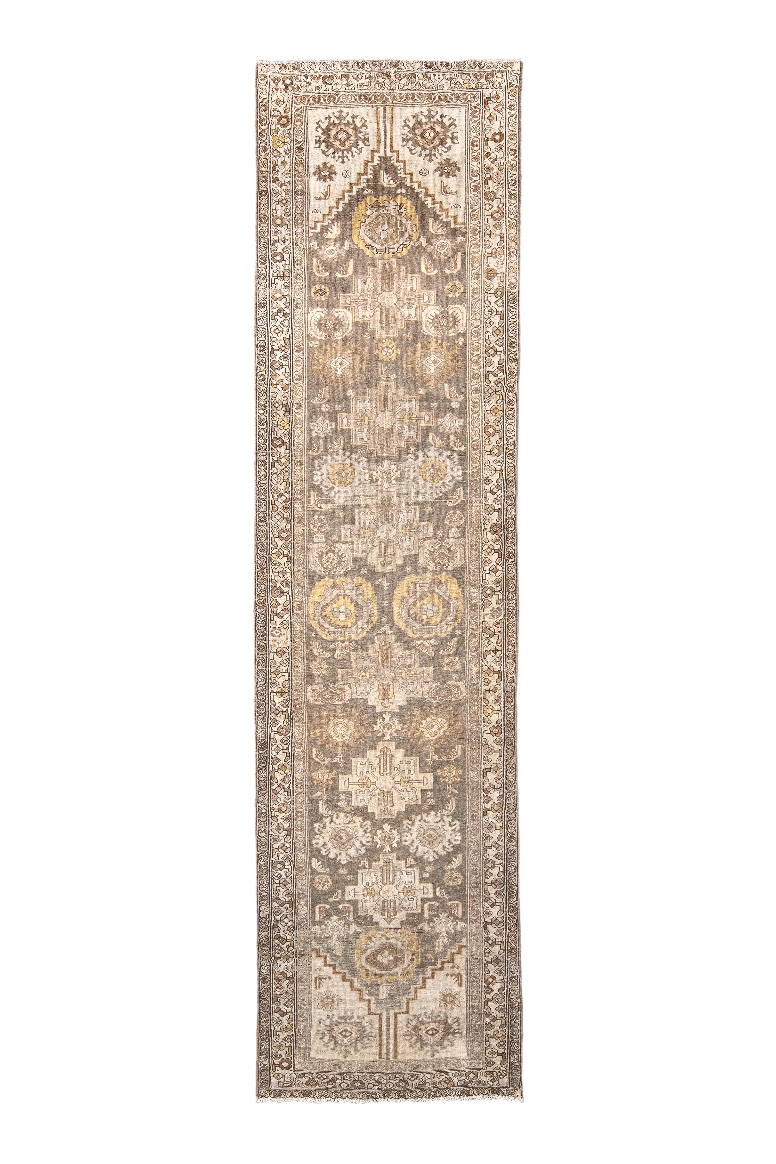 The panel abrashed slate field is step-pointed at the ends and shows a succession of round, nested palmettes, stepped medallions and ragged palmettes in sand, old gold, powder and dark brown, along with smaller lancet leaves. Ragged palmette/rosette