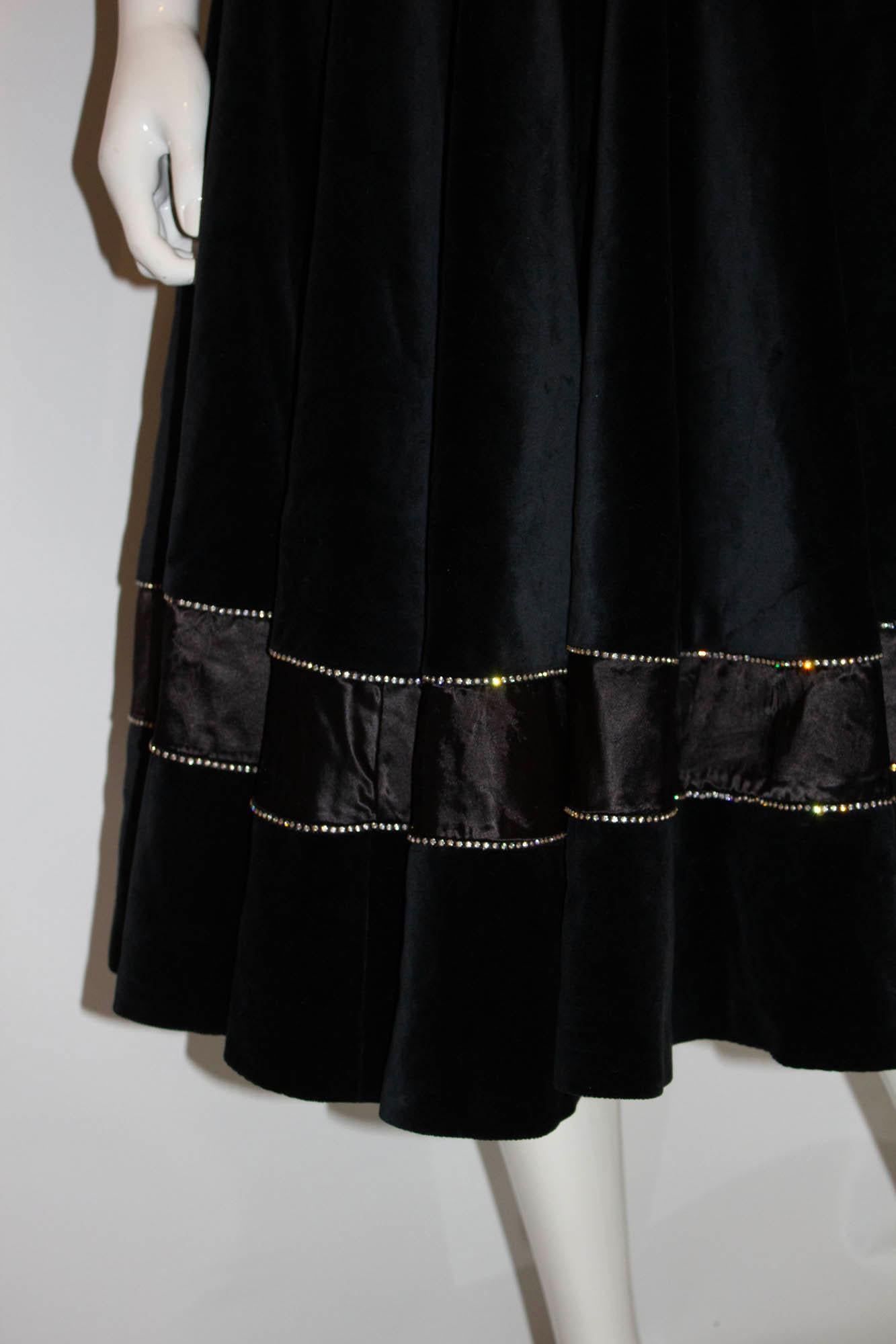 A wonderful skirt by Malcolm Hall, designer to the stars. The full skirt is in black velvet with diamante and satin detail near the hem. It is fully lined. Labelled size 12, waist 26'', length 30''