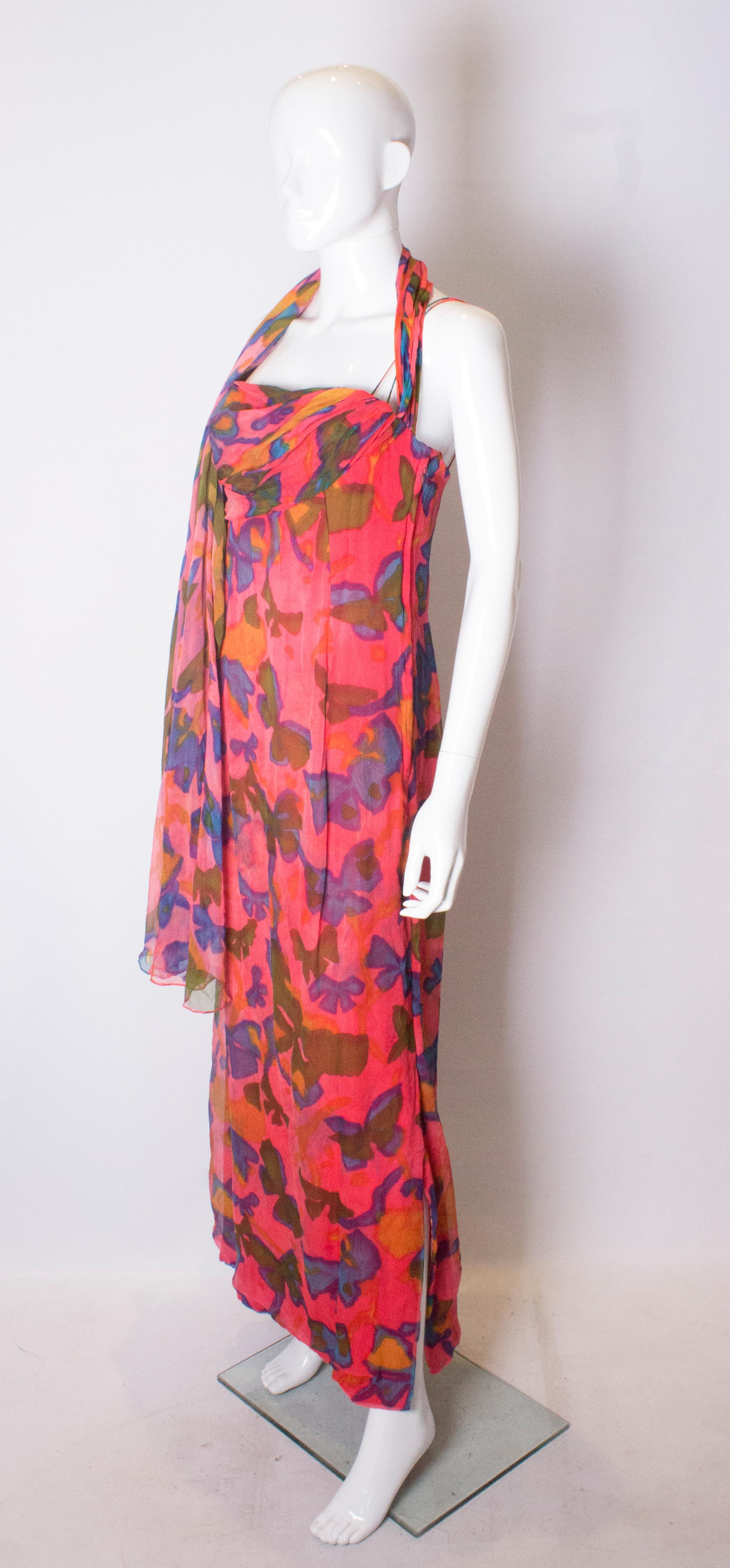 A stunning silk gown by Malcolm Starr. The dress is beautifully made with a boned bodice, double spagetti straps, and an attached scarf. The dress has a pink background with floral print.