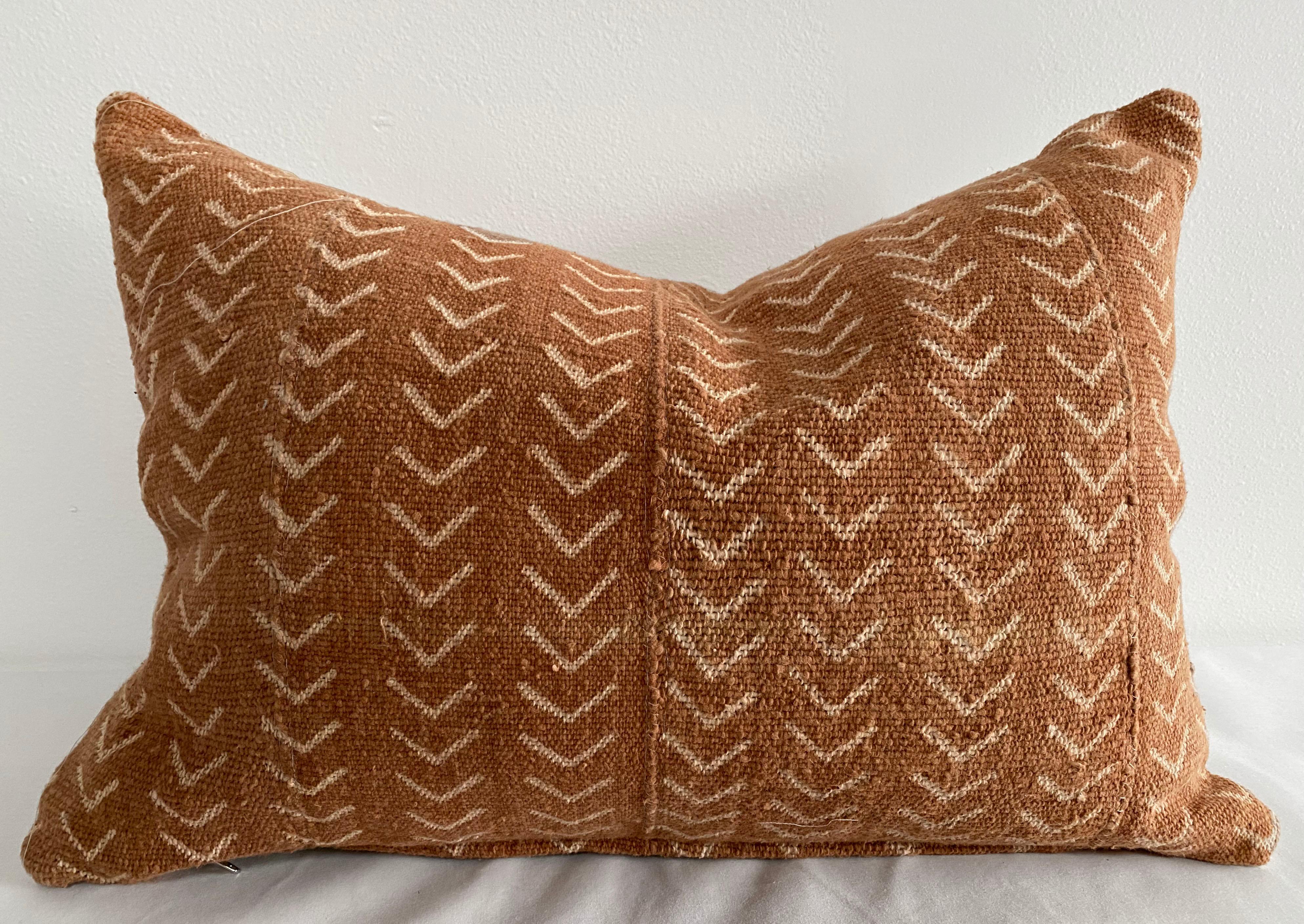 Vintage African Mudcloth pillows in a deep burnt orange rust color, with off white arrow pattern. Sewn with a zipper closure, and natural linen backing. The inside has an overlocked edge, can be machine washed on gentle. For color fading dry clean