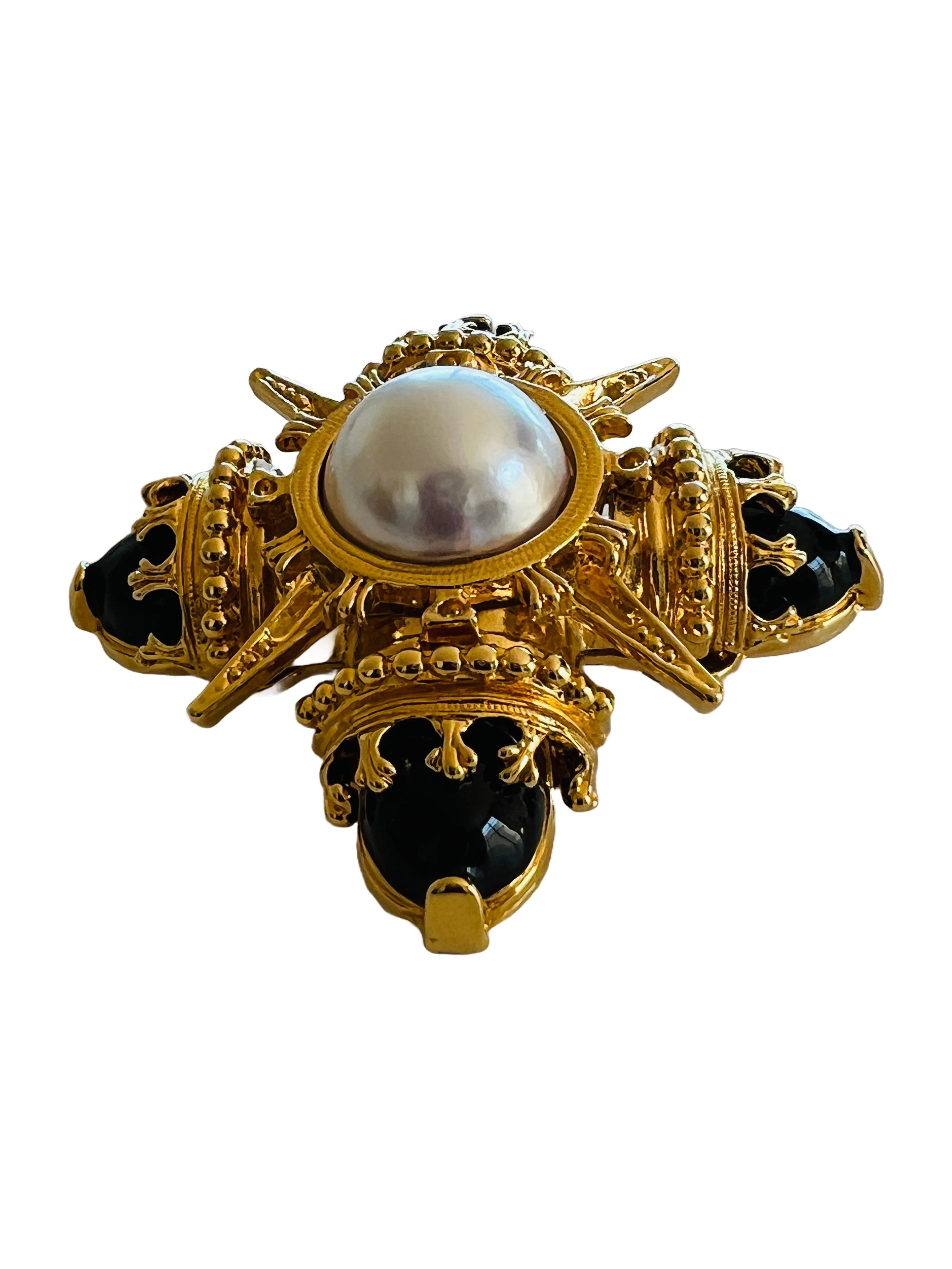 Add a touch of glamour to your outfit with this stunning vintage black and gold Maltese cross brooch. The intricate design features black enamel and a center imitation pearl cabochon set in yellow gold-plated metal. The brooch is a statement piece
