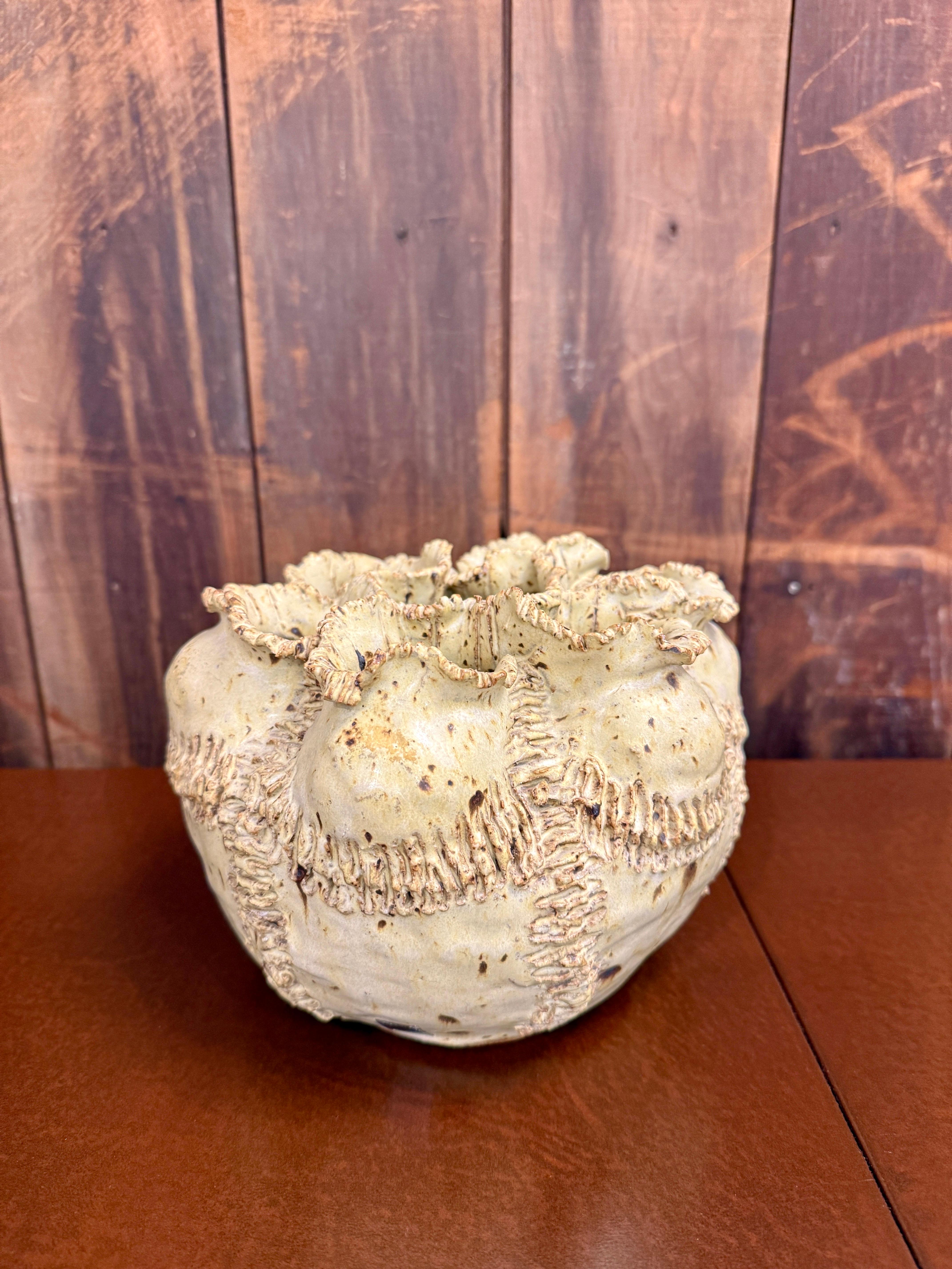 Ce vase en faïence incroyablement bien travaillé, fabriqué à Malte, présente des tons naturels et un sommet garni de rubans avec de multiples ouvertures.  Très belle pièce, lourde.