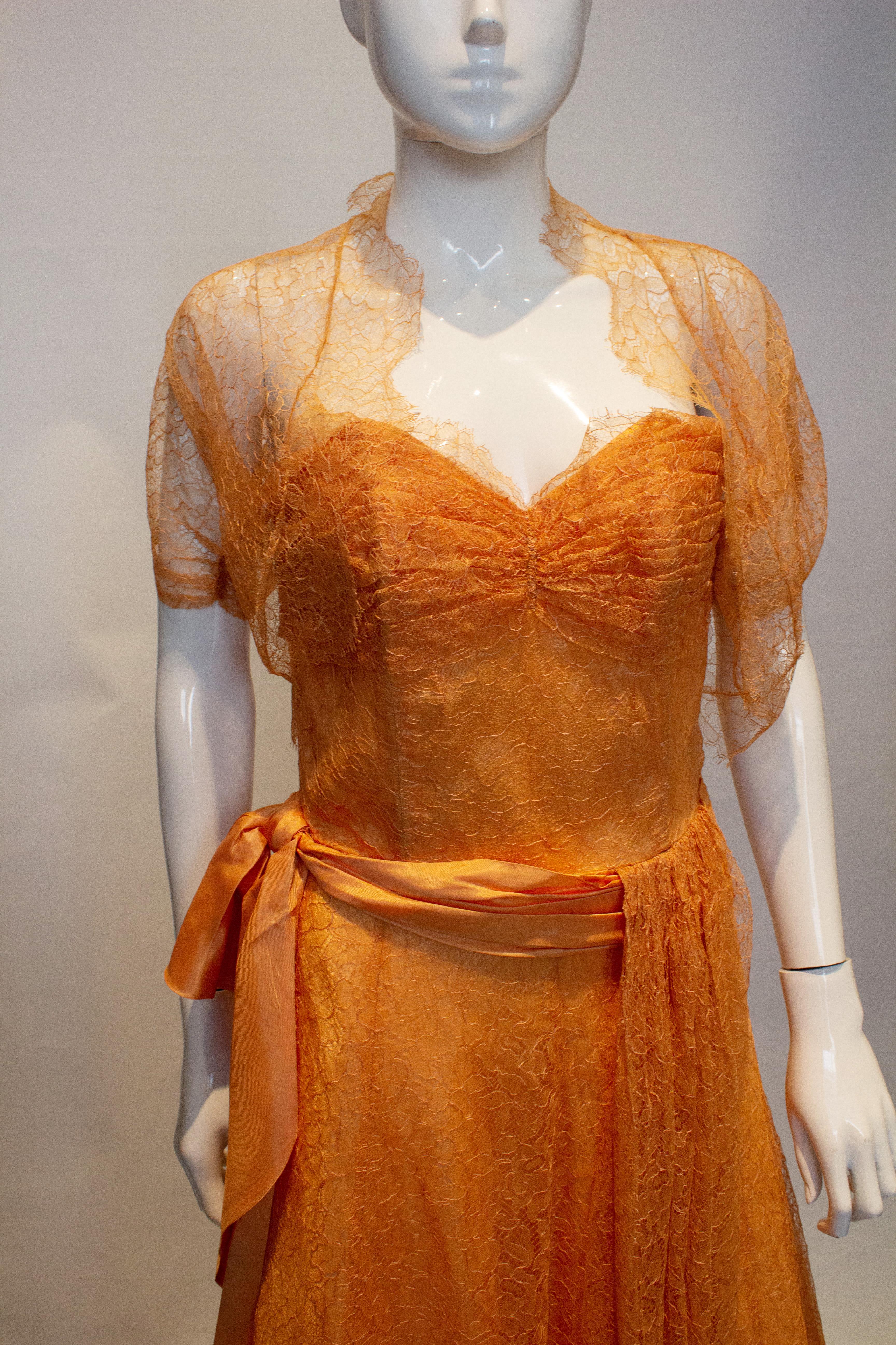 A pretty vintage dress in apricot colour lace  with a matching bolero. The dress is strapless with boning in the bodice and a side zip. It has a wide ribbon belt and a lace drape.
Measurements: Dress bust 36'', waist 28'', length 48''', Bolero bust