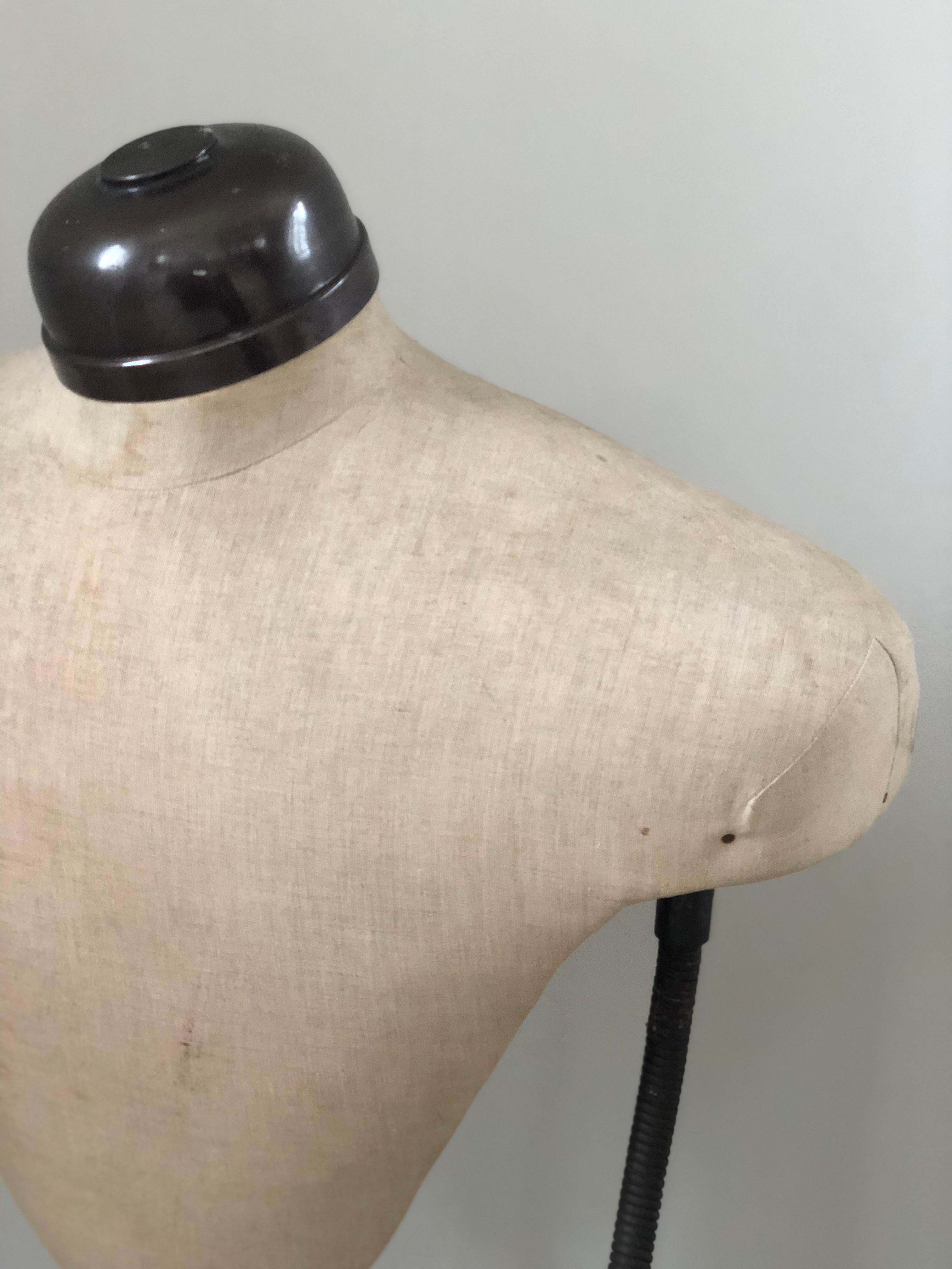 A vintage adjustable mannequin on a metal frame. Owned by a fashion store in Brussels, marked: Articles D'Etalages, A Delabye 17 Bd Poincaré Bruxelles. The history can be found.

Design of a sturdy torso dressed with linen and adjustable metal arms.