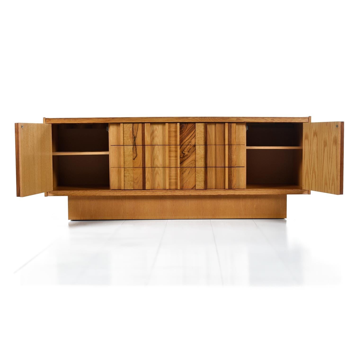 This stunning Brutalist credenza use several species of wood to create a truly unique look. The magpie assortment of veneers include maple, oak, burl wood, rosewood and walnut. The main body of the piece is a honey colored maple, fitting for this