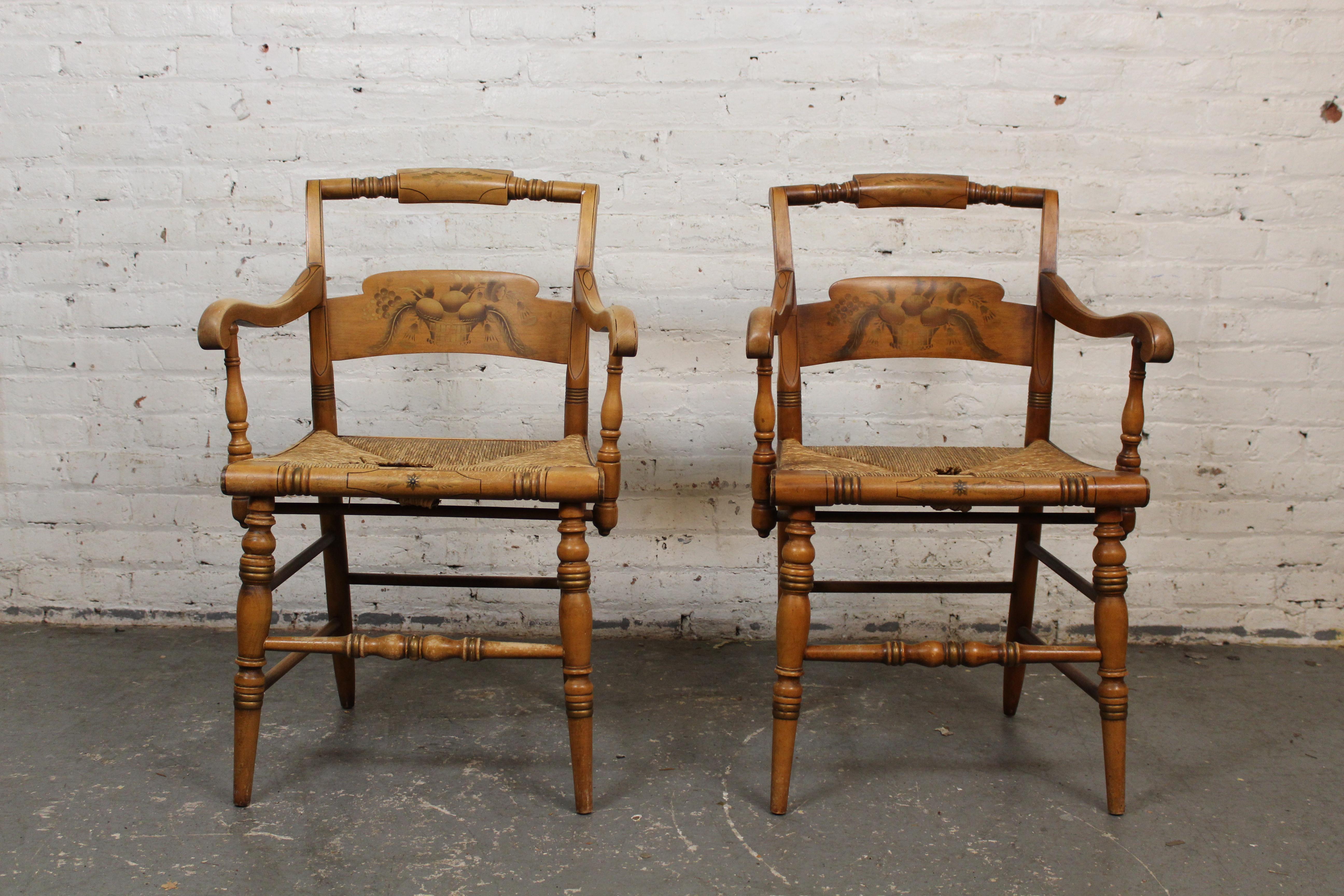 Charming pair of vintage harvest chairs produced by the second iteration of the legendary Lambert Hitchcock Chair factory of Riverton, Connecticut dating to the 1940s. A solid maple frame features turned bobbins and carved, arching arm rests. A