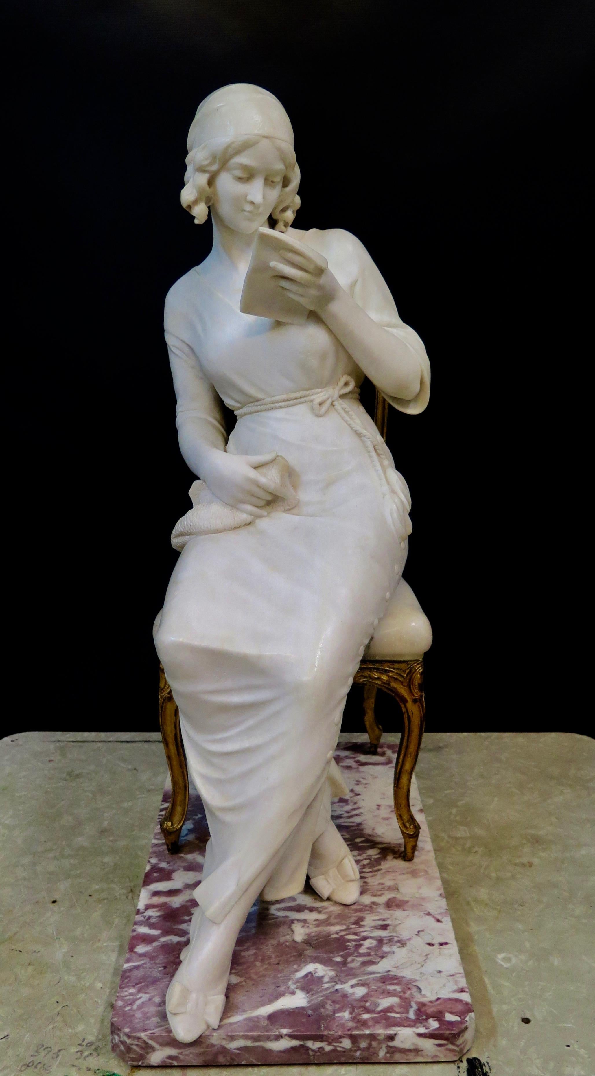 This vintage early 20th century hand carved marble sculpture depicts a lovely young lady dressed in fashionable attire of the time. The artist, Giuseppi Gambogi, portrays his subject comfortably seated upon a bronze chair reading, what appears to