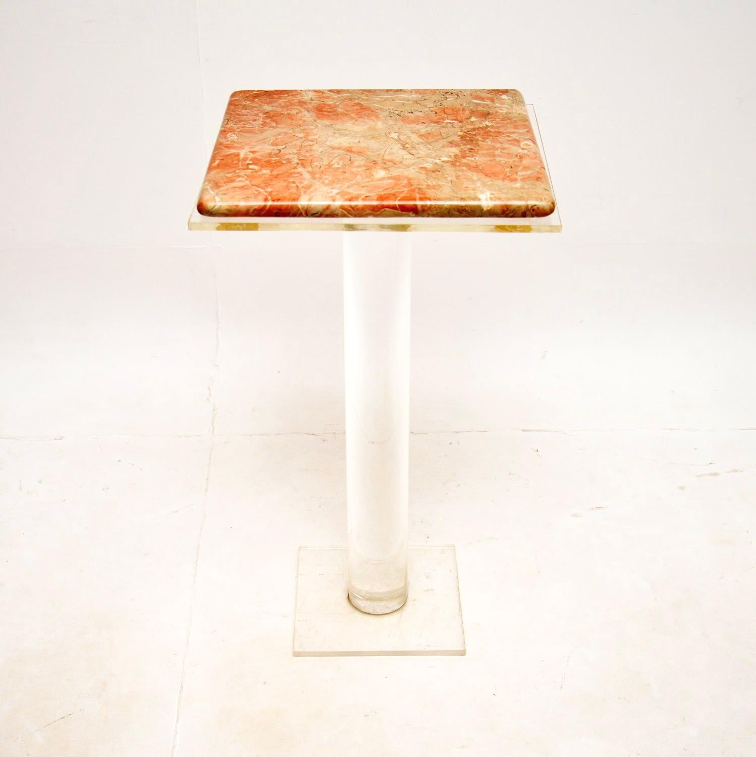 A very stylish and quirky vintage marble and lucite pedestal side table. This was likely made in Italy, it dates from around the 1980’s.

It has a gorgeous marble top with pink tones, that sits on a clear acrylic cylindrical base. This is perfect