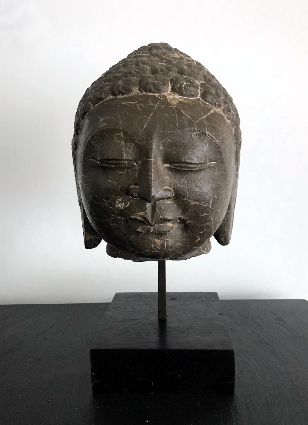 Carved out of a heavy block of dark brown marble with striking white veins, this Buddha head represents the Northern Qi style in China (550-577), but we believe that it was likely carved in the 20th century as a study for classic Buddhism sculpture.
