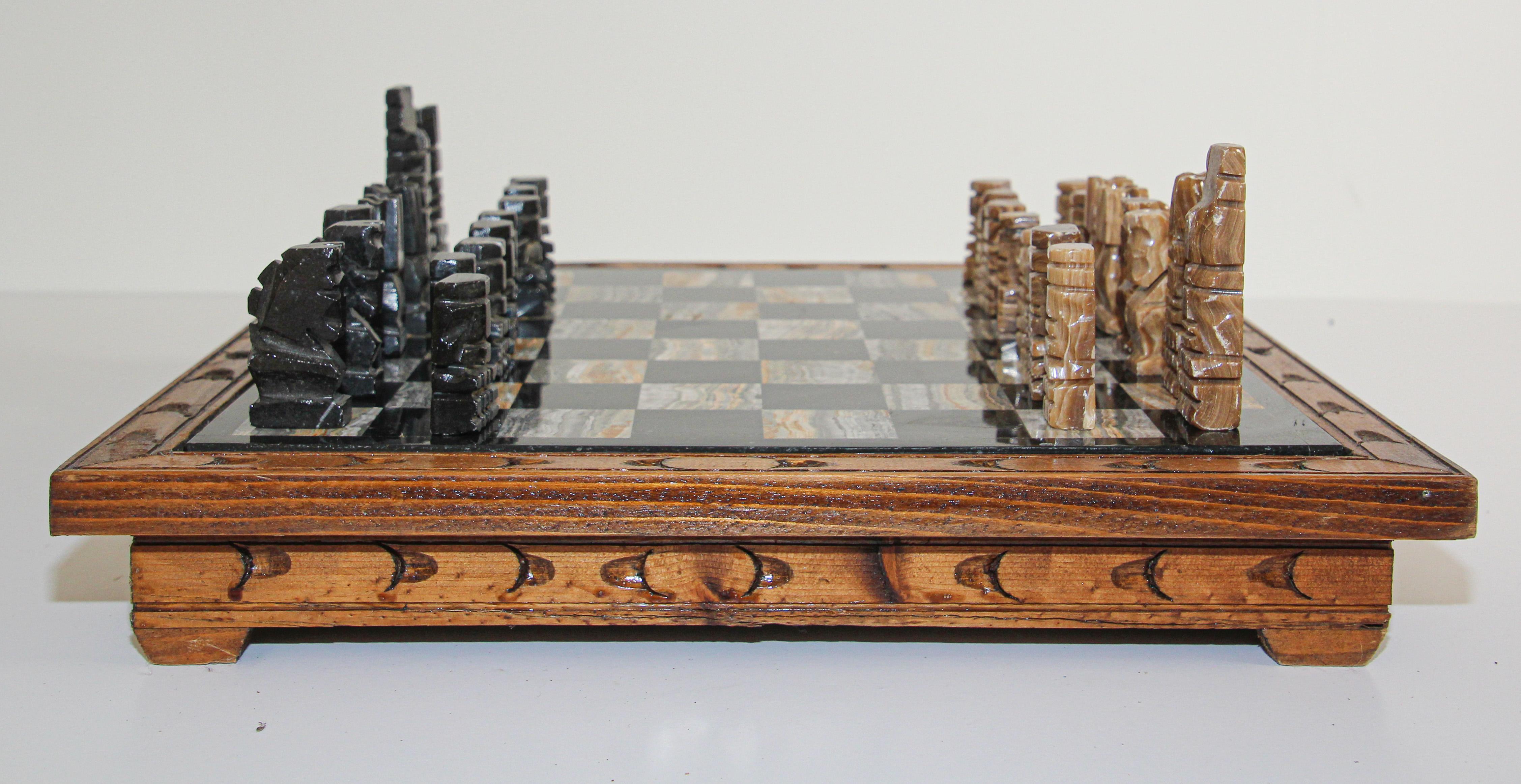 Vintage large heavy marble chess set complete board in brown and black with chess set with marble Mexican hand carved chess pieces.
Carved Aztec onyx black and beige chess pieces.
The chess board is mounted on a wooden handcrafted stand with