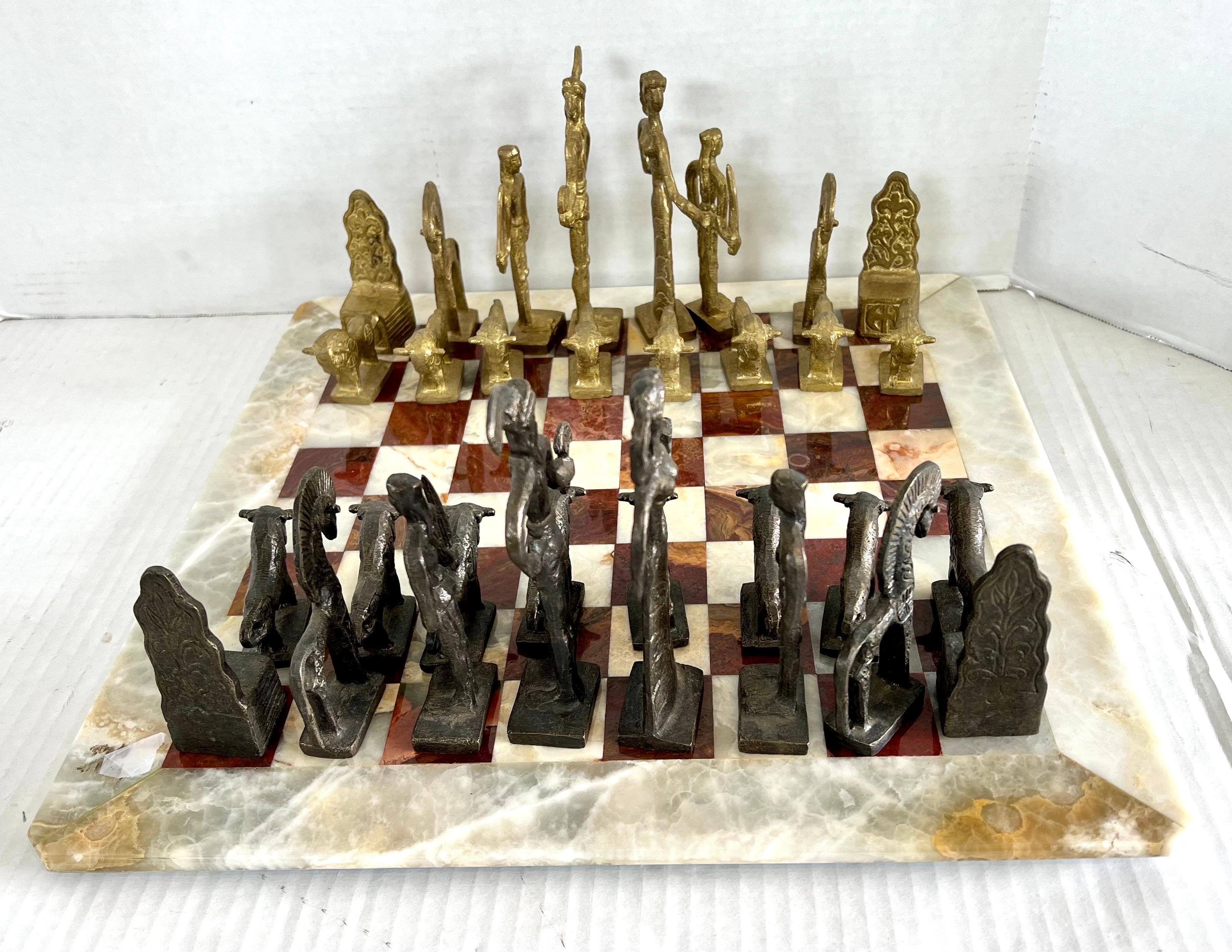 Vintage mid century chess set with marble game board and carved brutalist bronze and brass chess pieces. This set is very heavy and substantial. Measures: Game board is 3/4” thick. Tallest chess piece is 6” tall.
