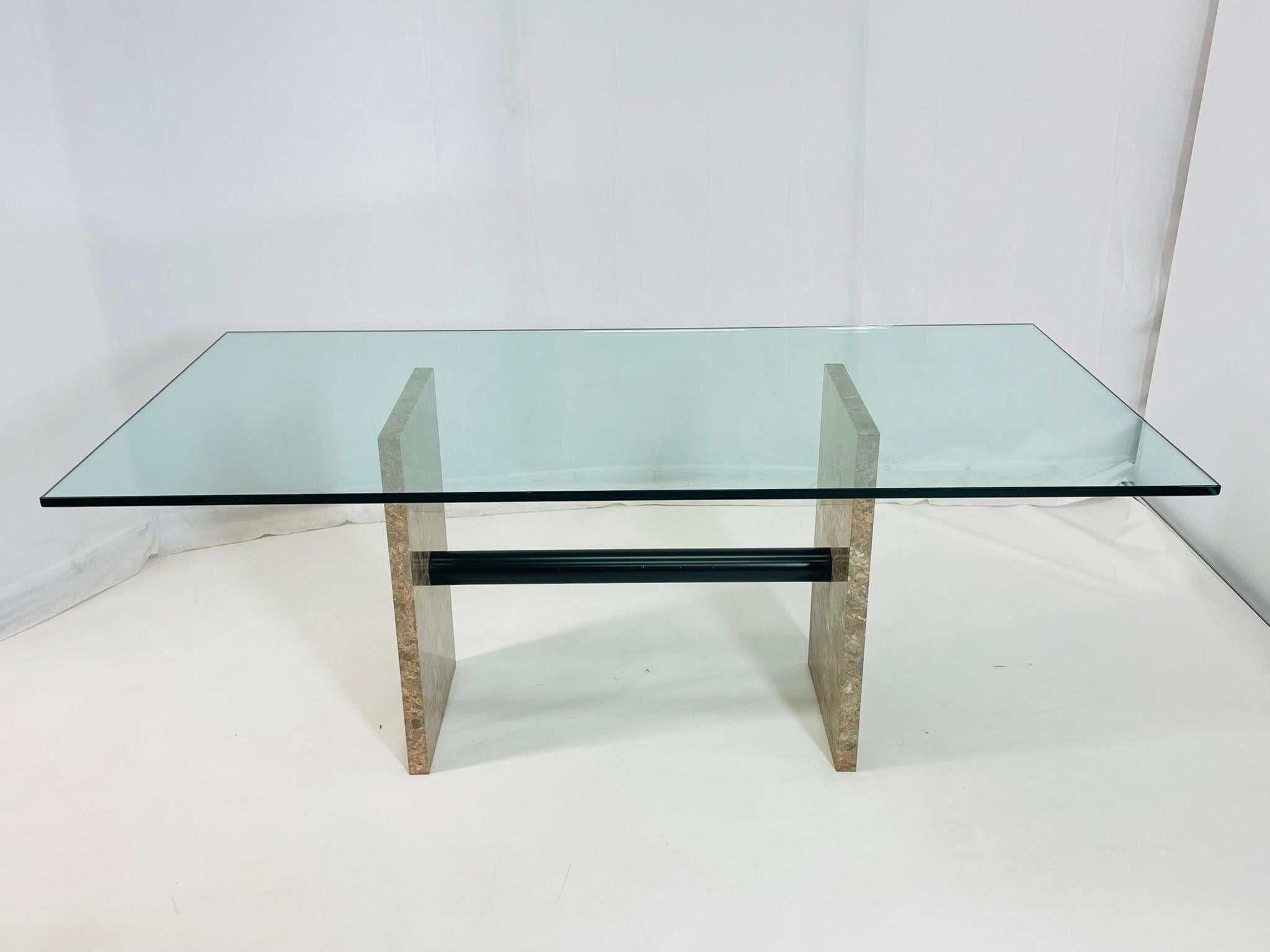 Tavolo da sala da pranzo moderno di metà secolo progettato e prodotto negli anni '70 in Italia.

Il tavolo ha una base in marmo con un'asta di metallo che sostiene i due pilastri in marmo.

Il tavolo ha un ampio piano in vetro con bordo smussato.

I