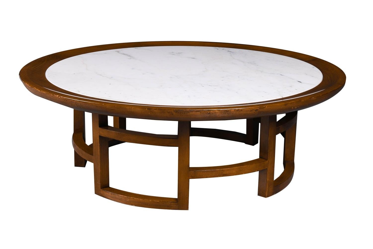 A stylish mid century round marble top coffee table in the manner of James Mont, by Warsaw Furniture Company circa 1950's. This vintage marble and wood table features original circular white Carrara marble top, inserted in a fluted rim supported by