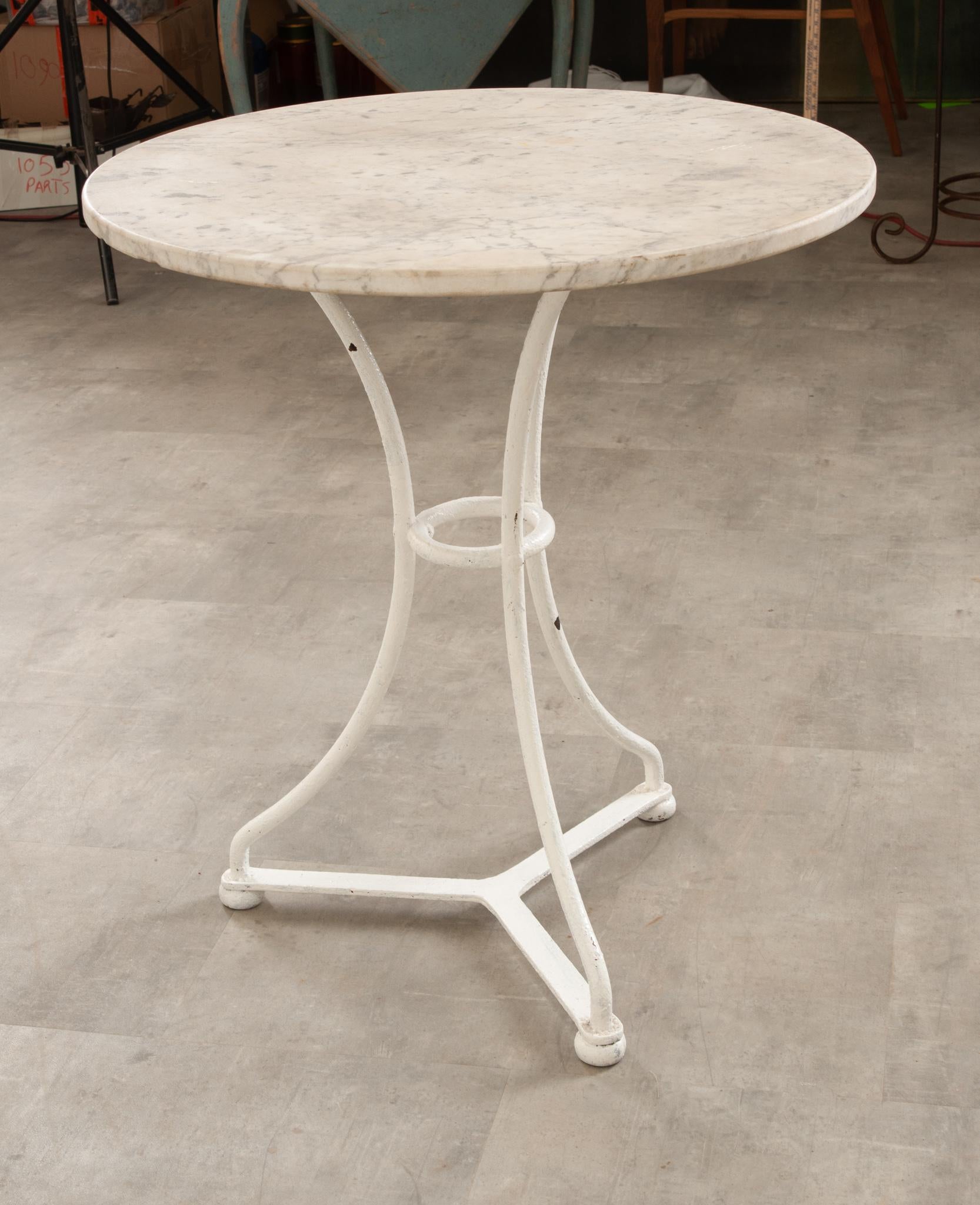 This petite vintage bistro table is perfect in any space! The worn white marble top is in great condition and beautifully compliments the white painted cast iron base. Three legs join at a center ring and at the feet with a three-prong bracket.
