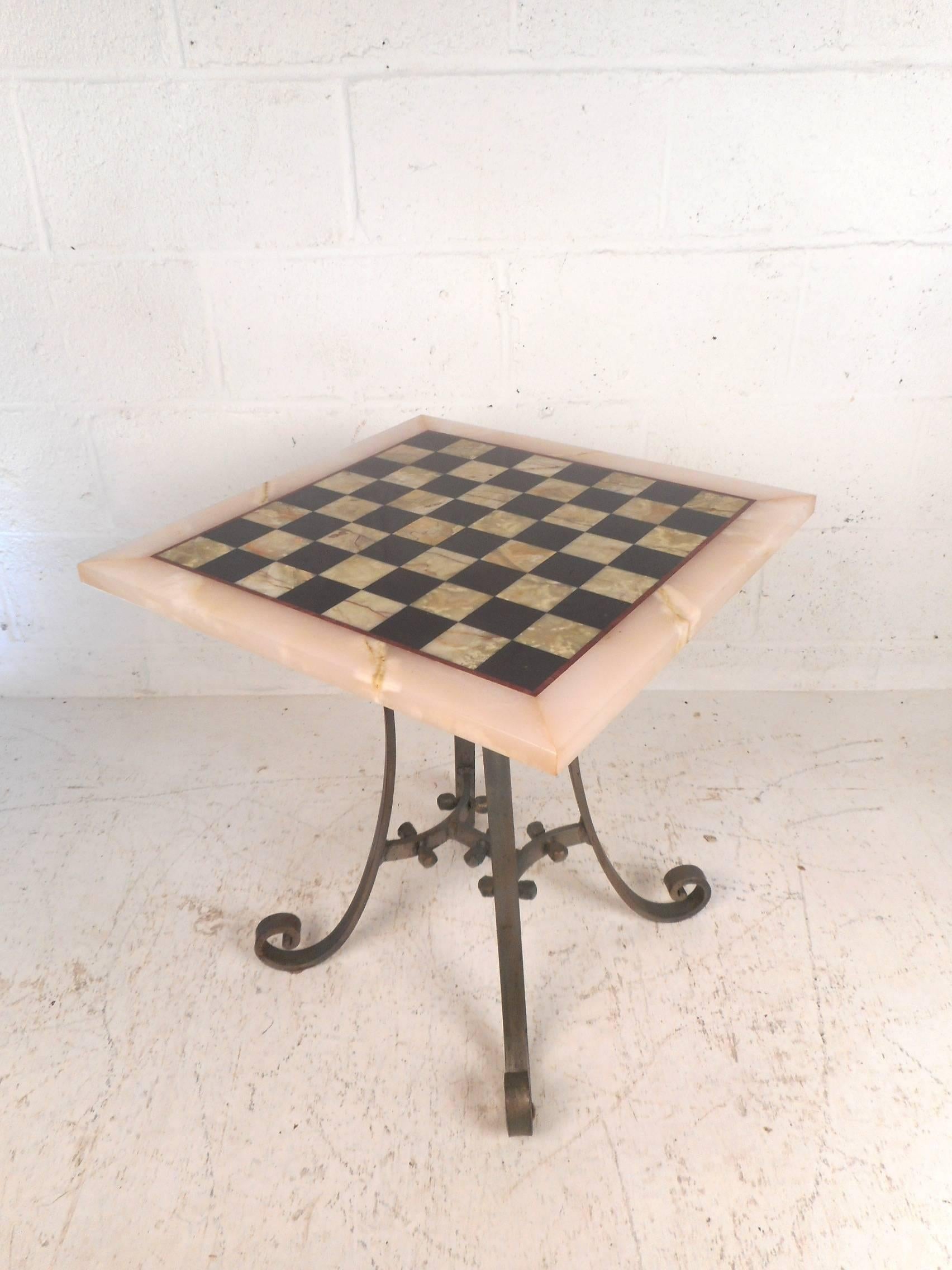 A stunning midcentury game table with a heavy cast iron base. This unique side table has a marble top with a chessboard inlay on it. A flat bar iron base with scroll detail holds up the heavy marble top. A great design that can function as a
