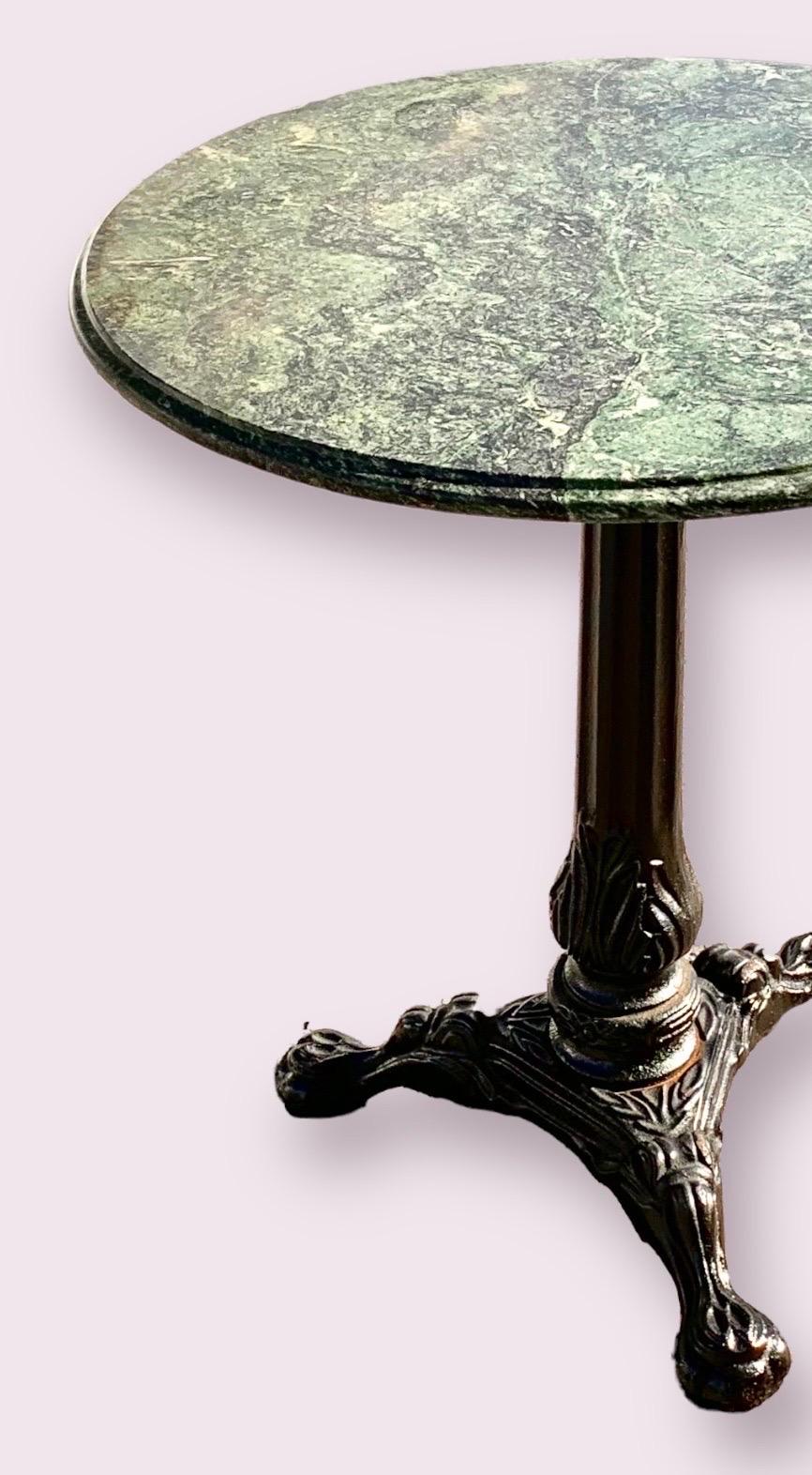 A vintage marble top, heavy cast iron tripodal base bistro table. Seats two. 
A charming addition to your breakfast area, keeping room or garden room. 
The Grecian marble is Verdi Antico with beautiful shades of dark green, black and touches of