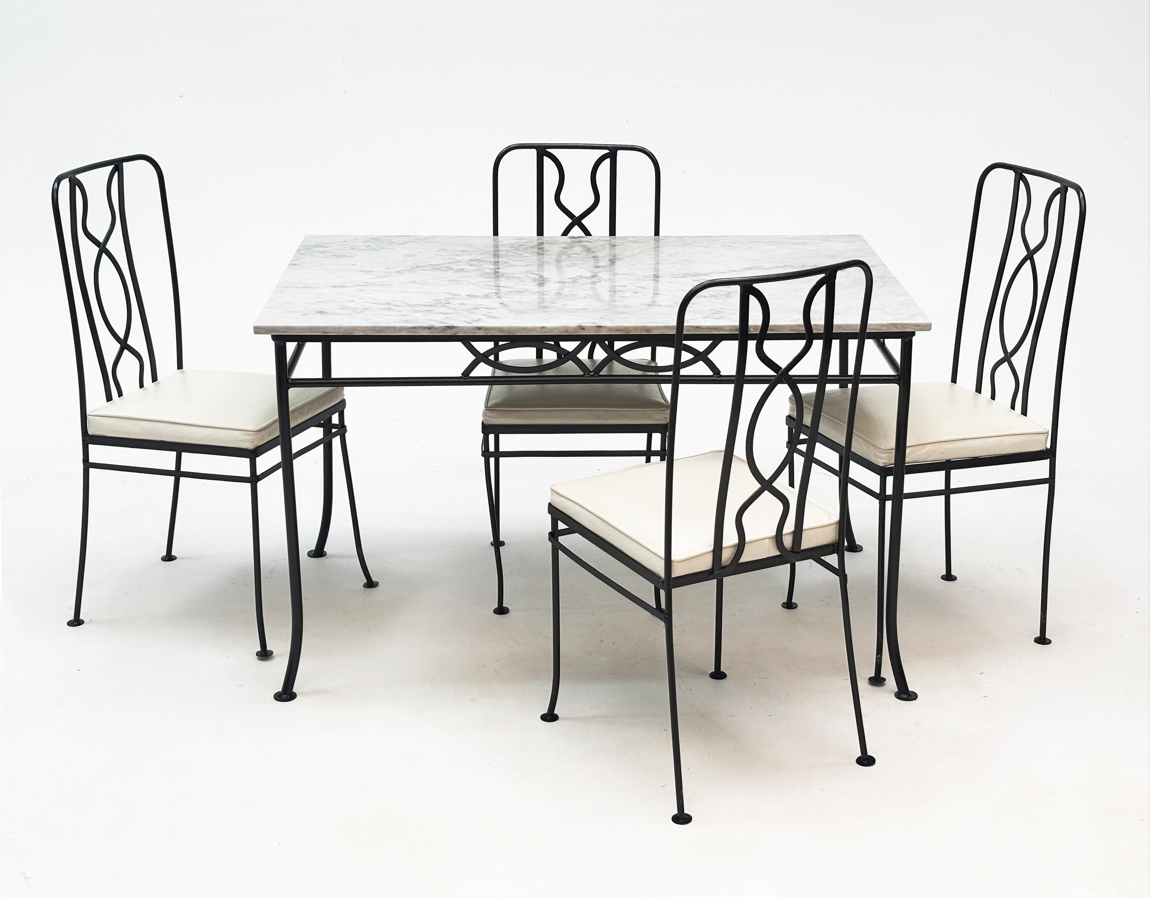 Esta mesa de patio vintage de los años 70, de hierro forjado y tapa de mármol, y sus cuatro sillas forradas de vinilo son tan sofisticadas como cómodas. Las sillas tienen sus revestimientos originales de vinilo blanco. Uno de los asientos tiene un