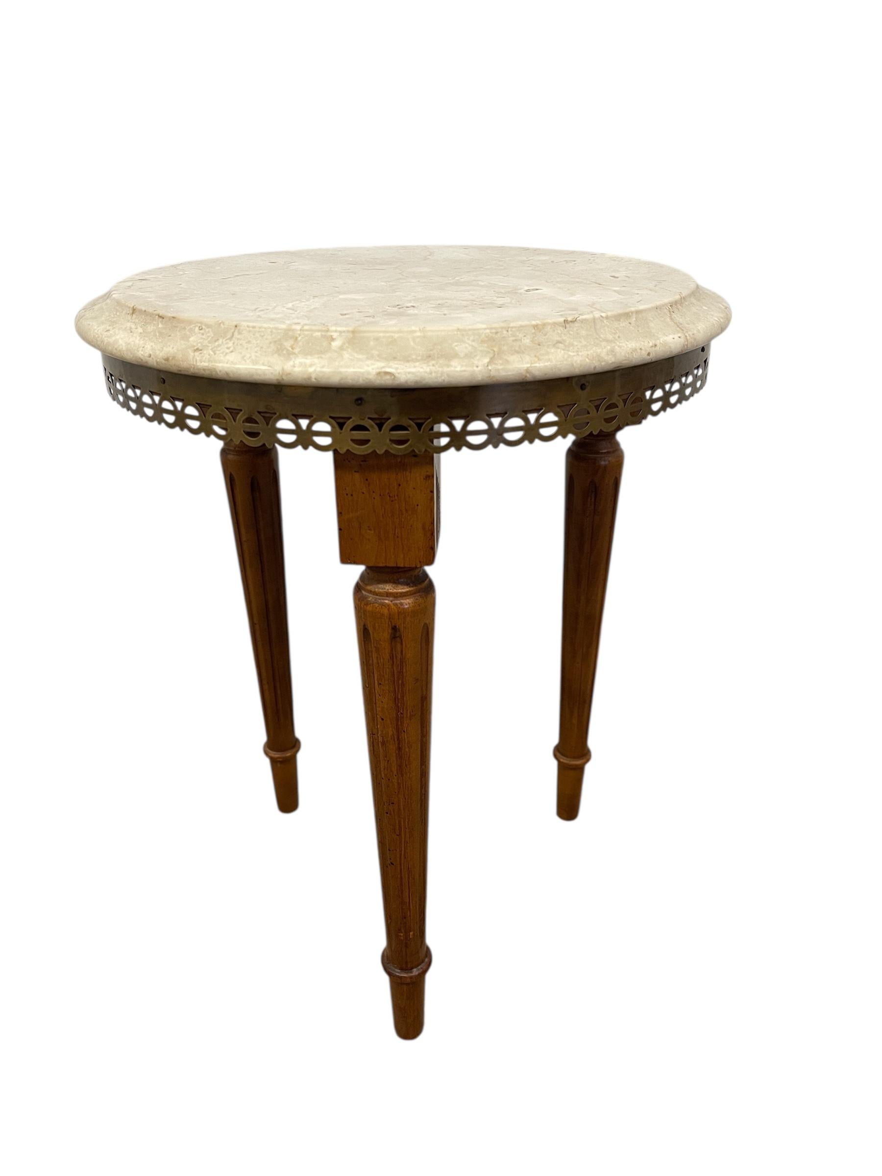  Questo tavolino vintage è caratterizzato da una raffinata miscela di materiali e dettagli di design che evidenziano la sensibilità decorativa dei primi anni del XX secolo. Il piano circolare è realizzato in marmo lucido color crema con venature