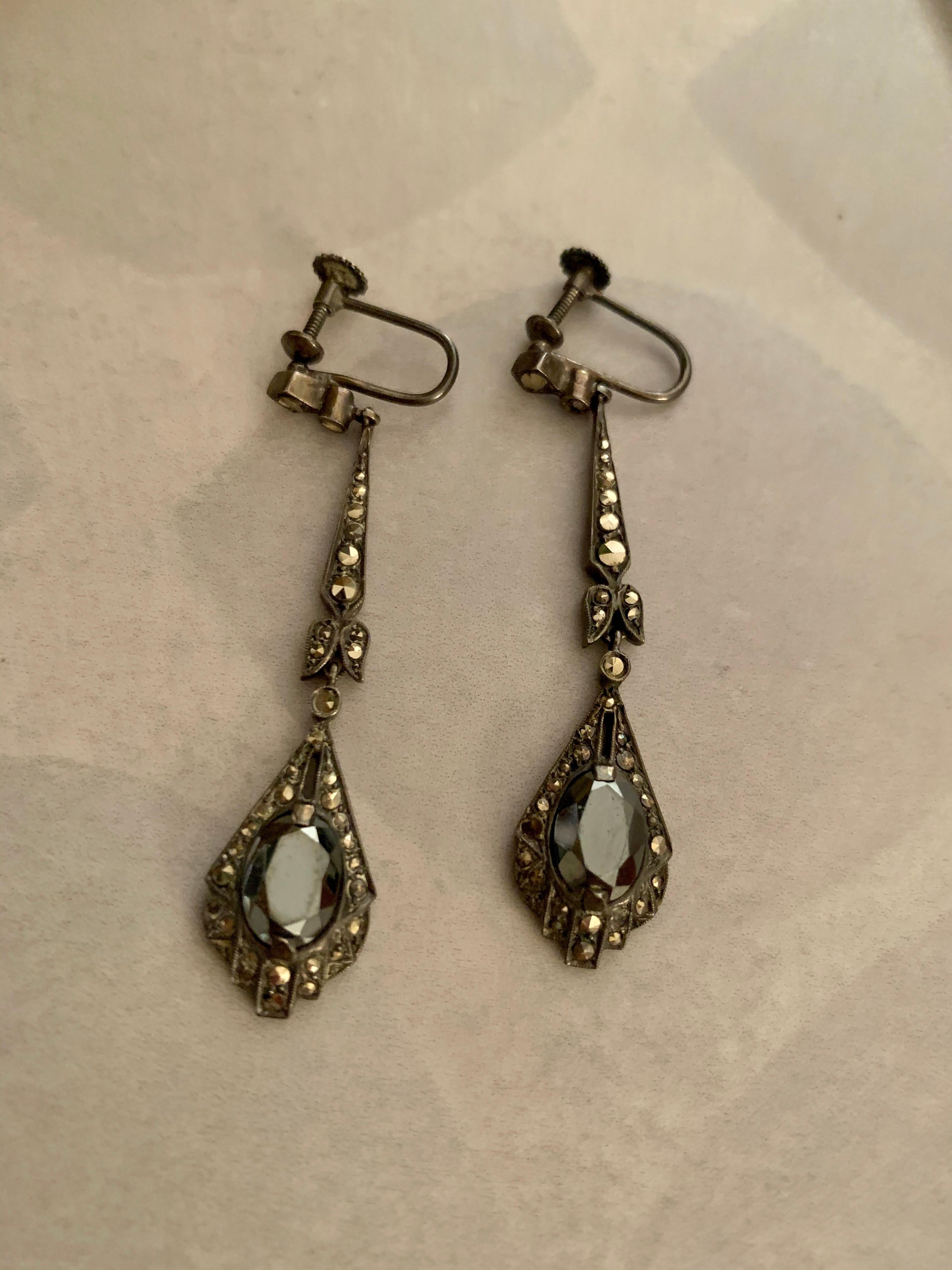 These lovely vintage earrings feature a drop which is a faceted Hematite stone, surrounded by Marcasite accents.  The Marcasite extends up to the closure, which is a screw back. 

Measurement:  12 x 52mm
Weight:  8.1 grams