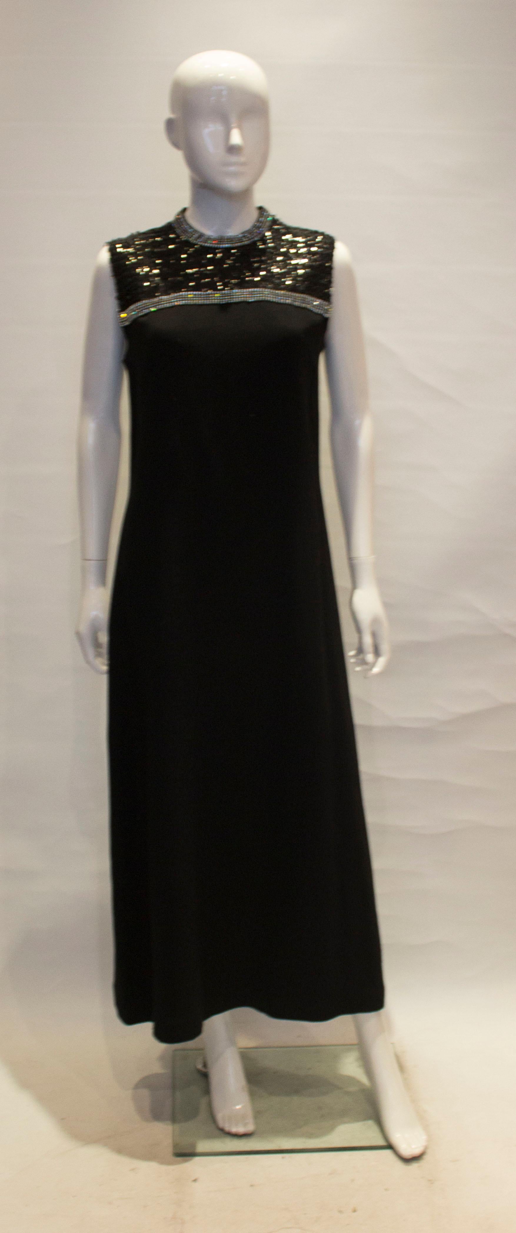 A chic evening gown by Marcel Fenez for Roland Klein. In a black  crepe , a line in shape the dress has a diamante and sequin bust area and central back zip.