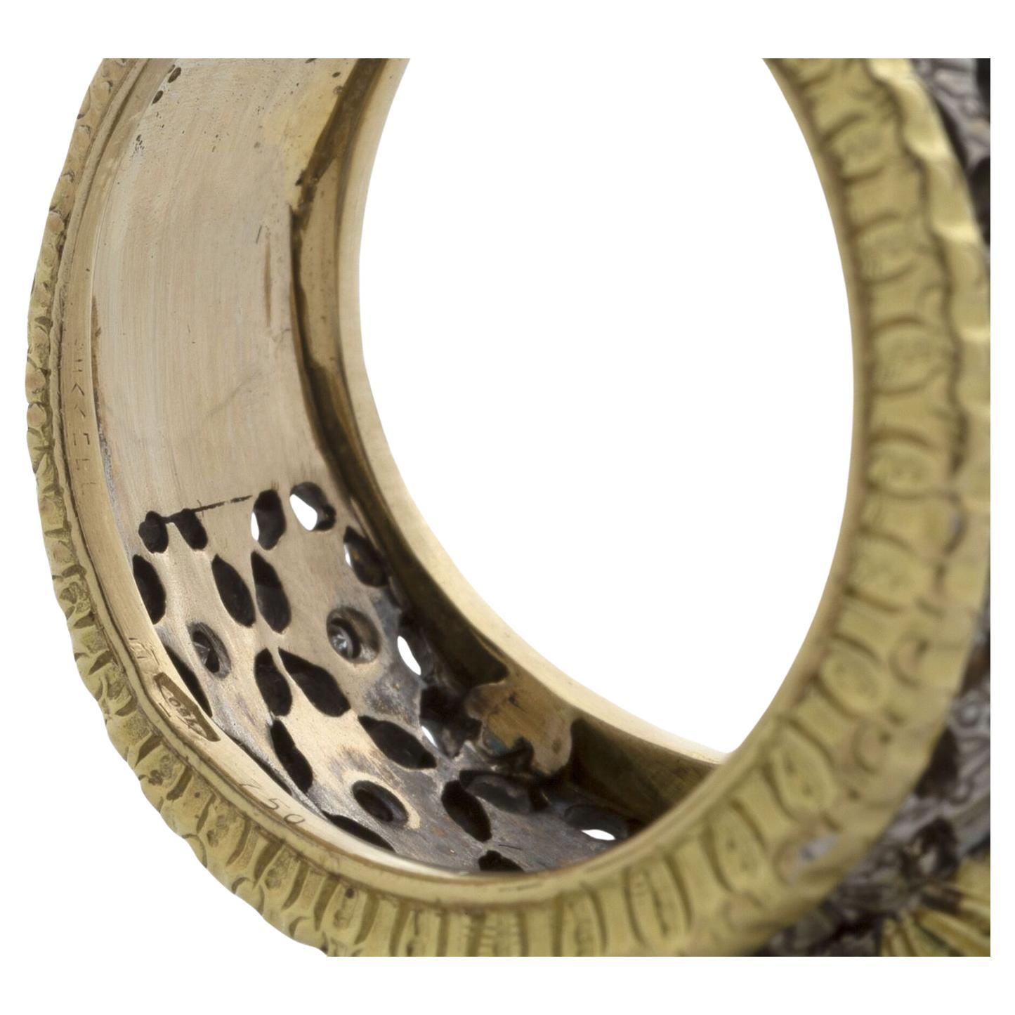 The bicoloured openwork band set with brilliant-cut diamond accents, with a central oval-cut sapphire of approximately 1.5 ct, signed M Buccellati.

Ring size: 7 1/4
Weight: 12.10 gr.