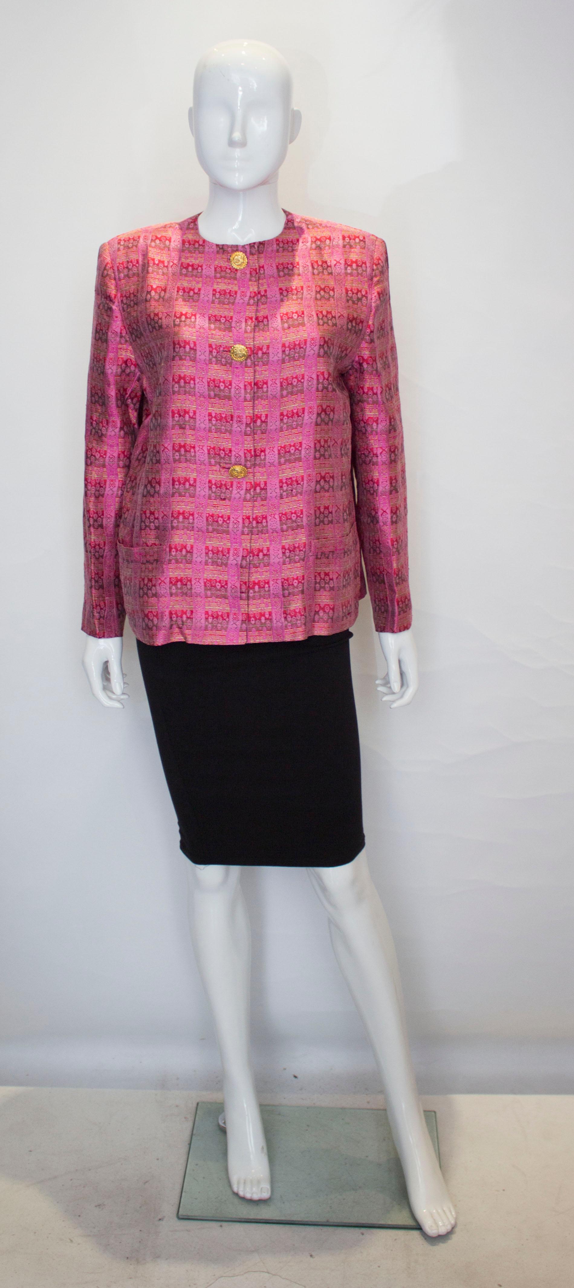 A pretty pink vintage silk jacket by Mario Valentino. The jacket is in pink with kahki, red and pale green detail. It is collarless with central front button fastening. It has a pocket on either side at hip leval.