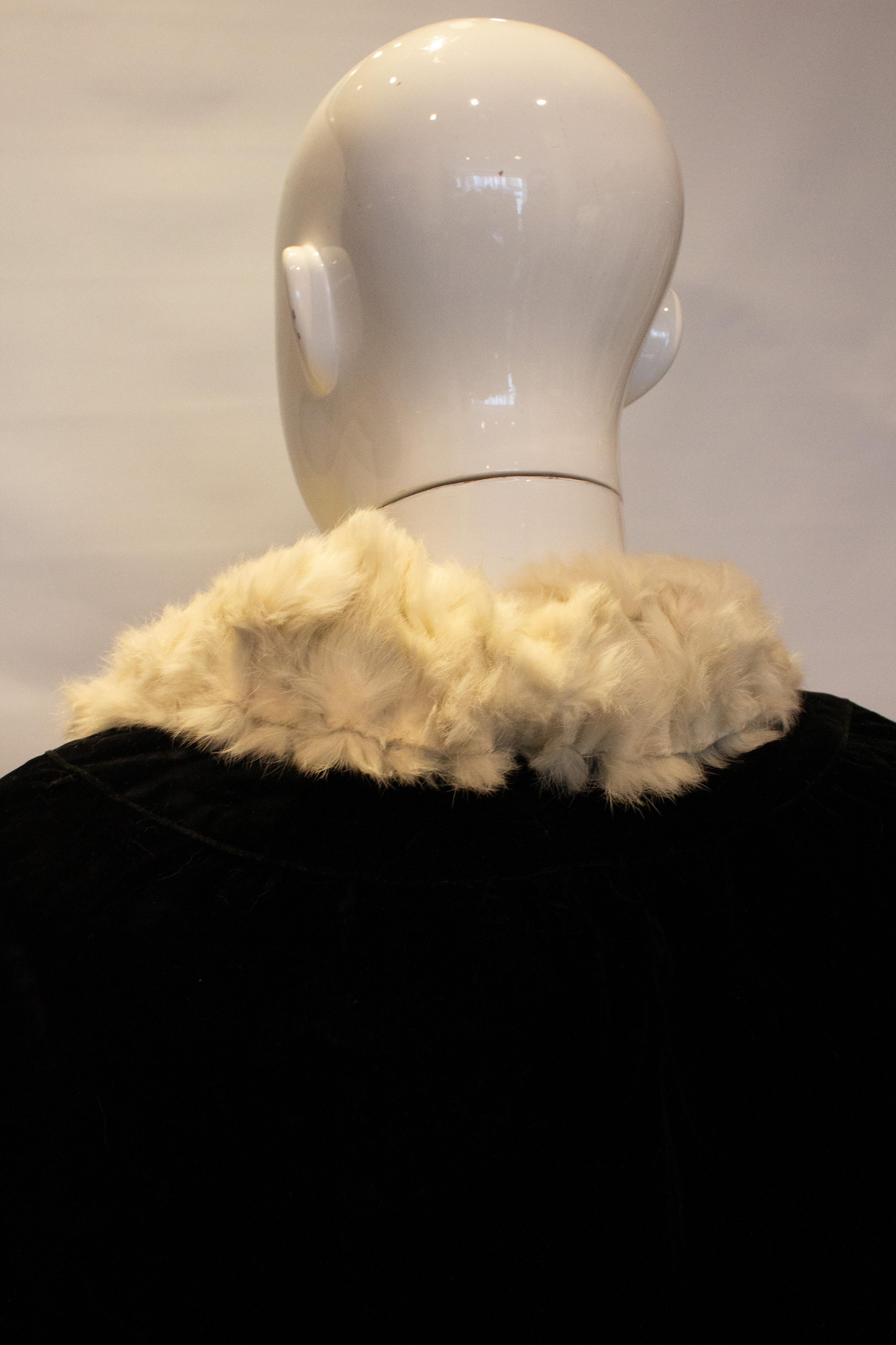 A stunning vintage cape by Marshall and Snelgrove. The cape is in black velvet with a white fur lining. It has one internal pocket and a single button fastening at the neck.
Measurements :  Shoulder to shoulder 19'', length 39''