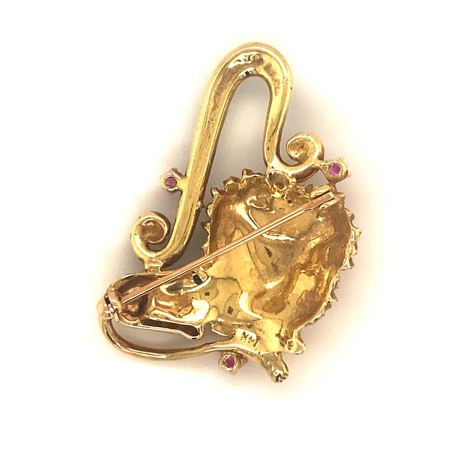 This is a beautiful brooch is designed with a lion and Leo sign with green enamel and rubies in 14k gold.  The brooch is marked with a maker’s mark Mart and 14k.  The three rubies are round natural and measure .24 carats. The lion has red enamel