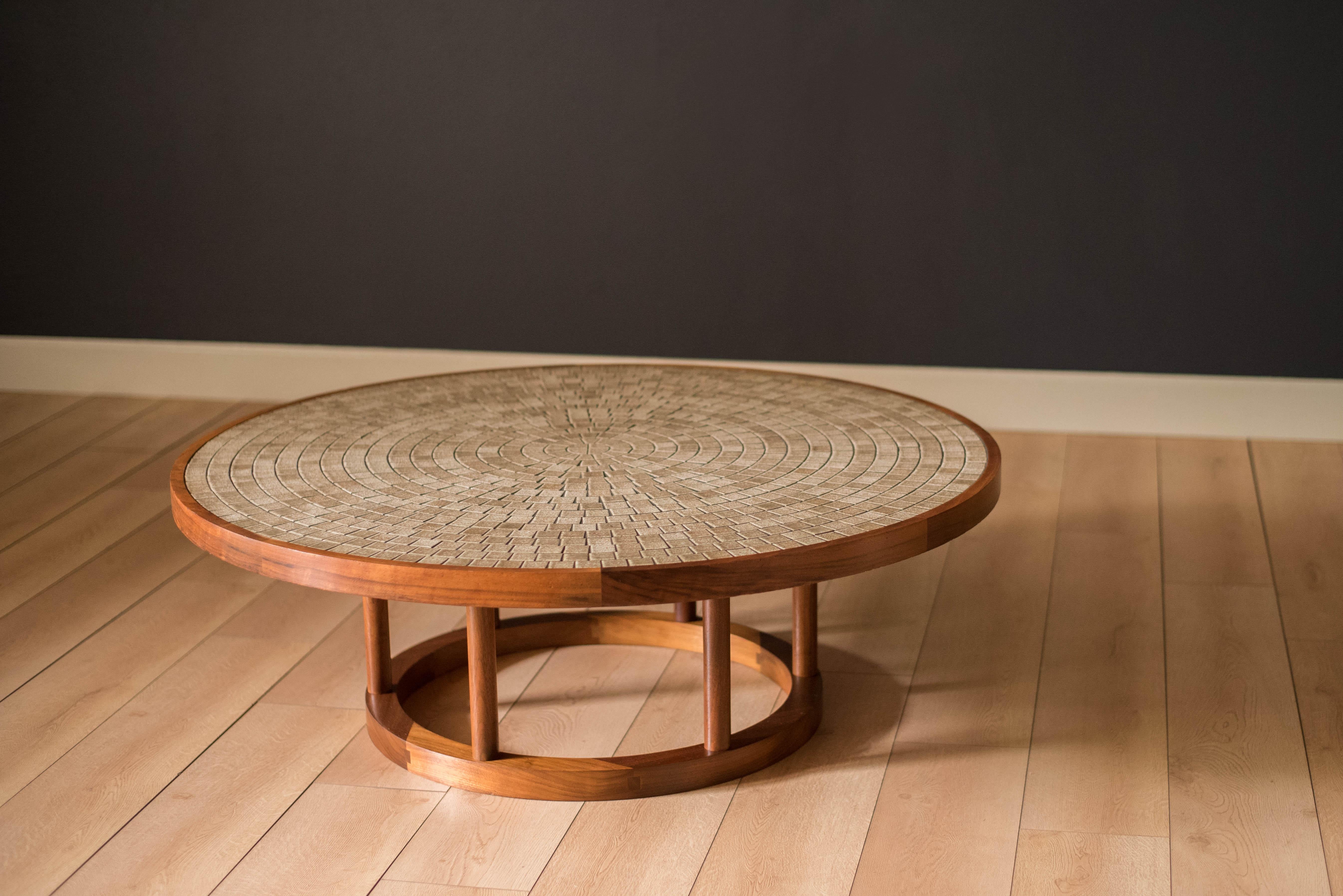 Mid-Century Modern coffee table designed by Jane and Gordon Martz for Marshall Studios. This piece features a round tabletop inlaid with stoneware tile in a textured tan and cream matte finish. Sturdy pedestal ring base is made of black walnut and